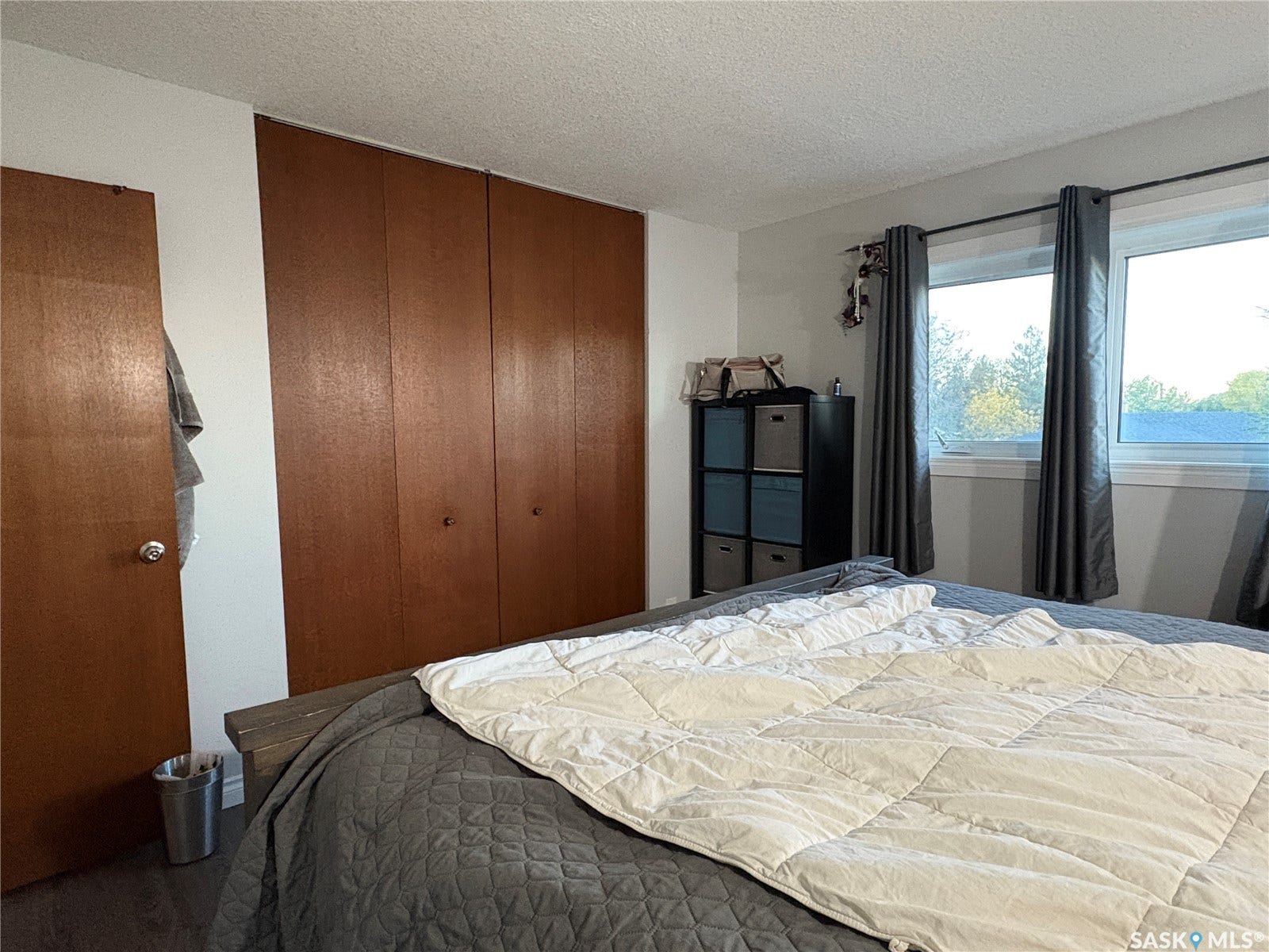 Wood-finish bi-fold closet doors, white walls, and a wood-finish interior door