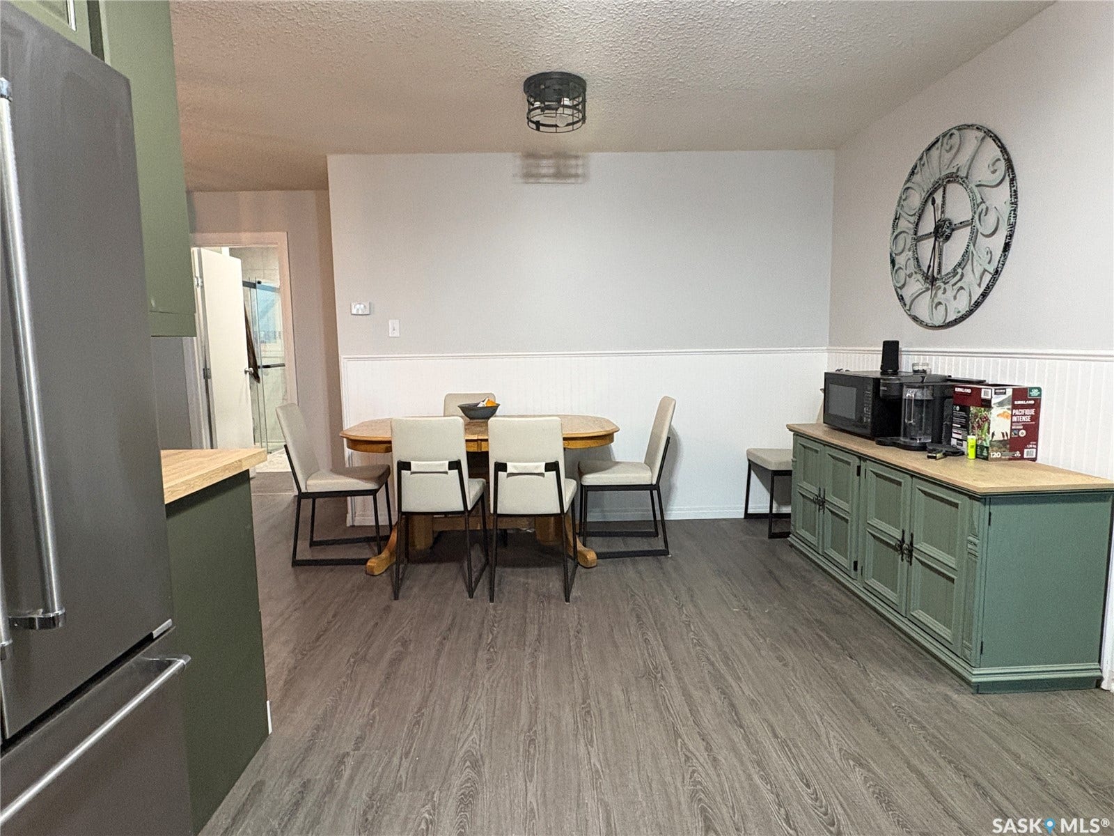 Wood-finish flooring, white wall paneling, and an overhead semi-flush mount light fixture