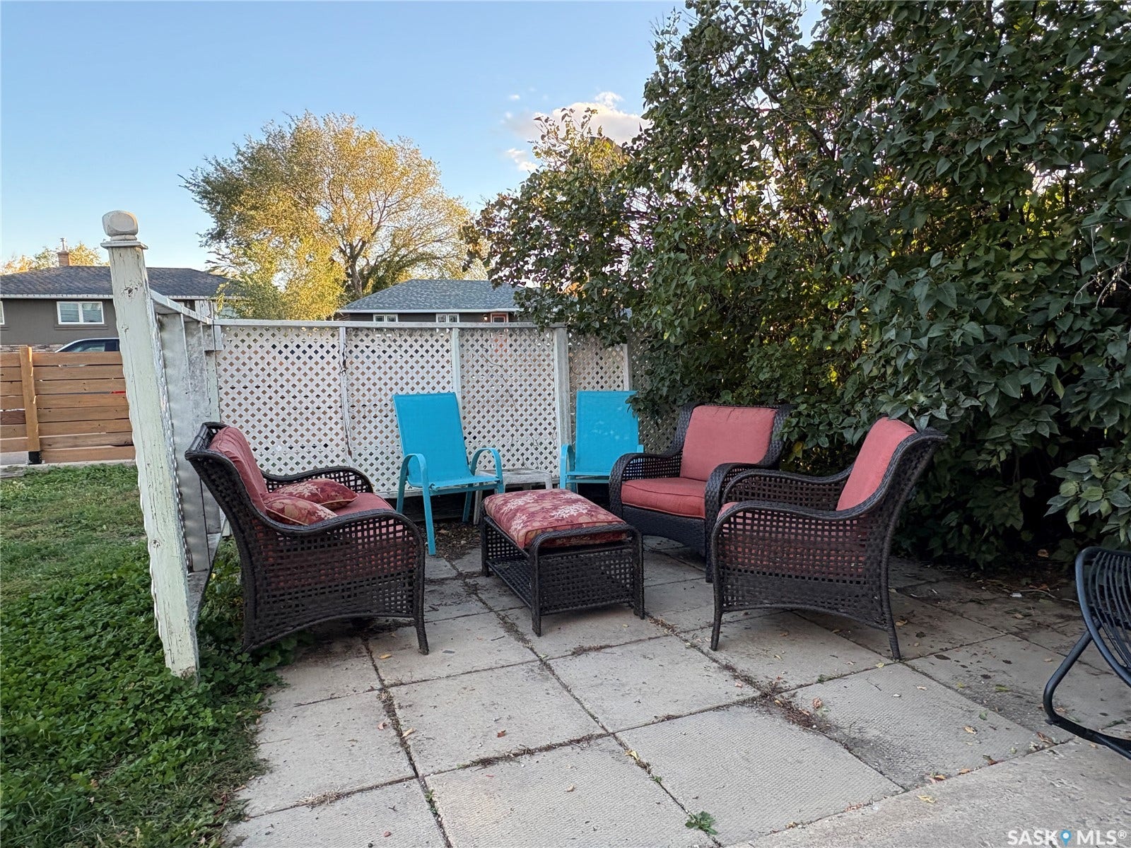 Backyard patio with concrete pavers, surrounded by a lattice fence and mature greenery