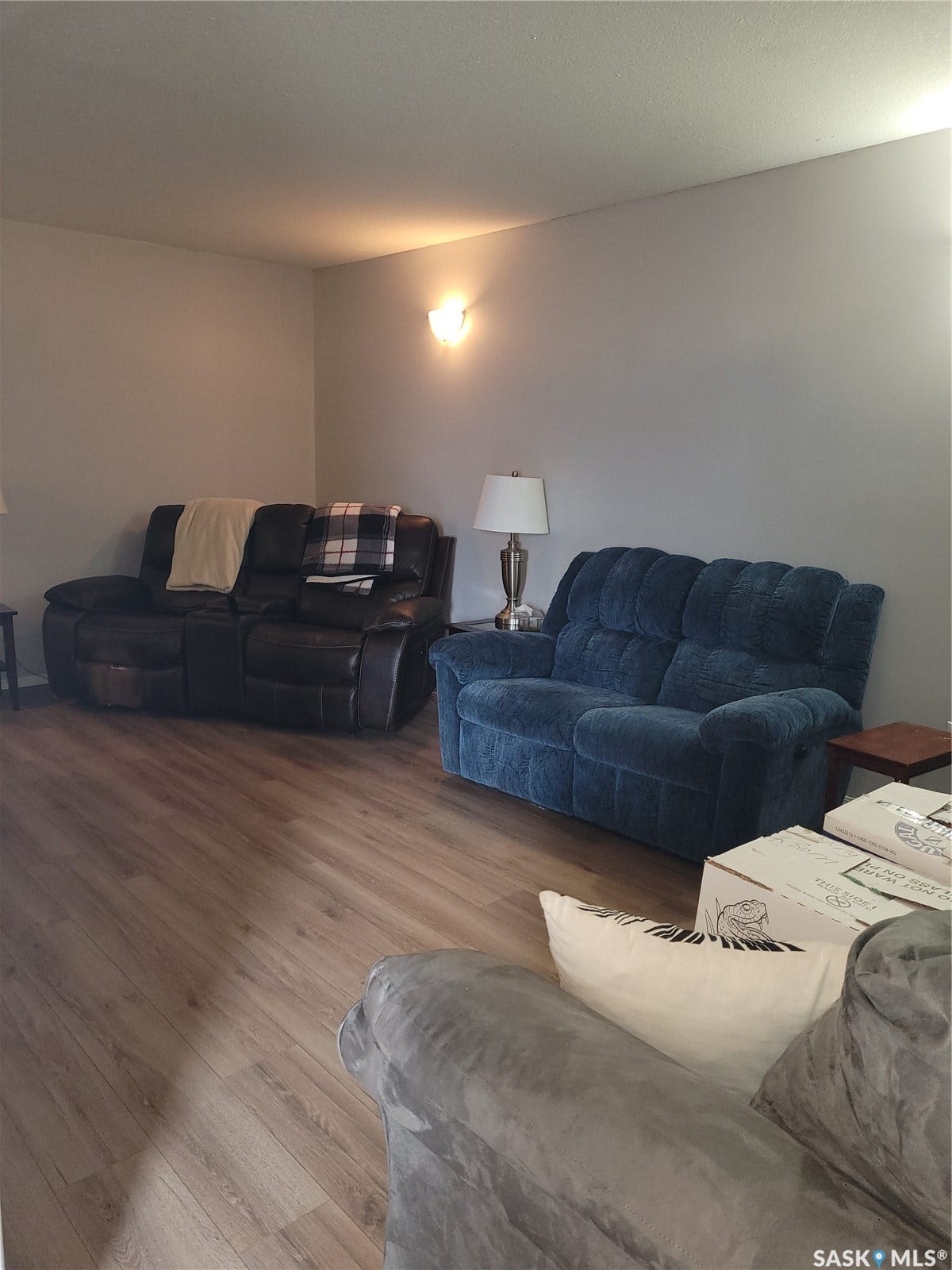 Wood-finish flooring with a neutral wall color and sconce lighting fixture