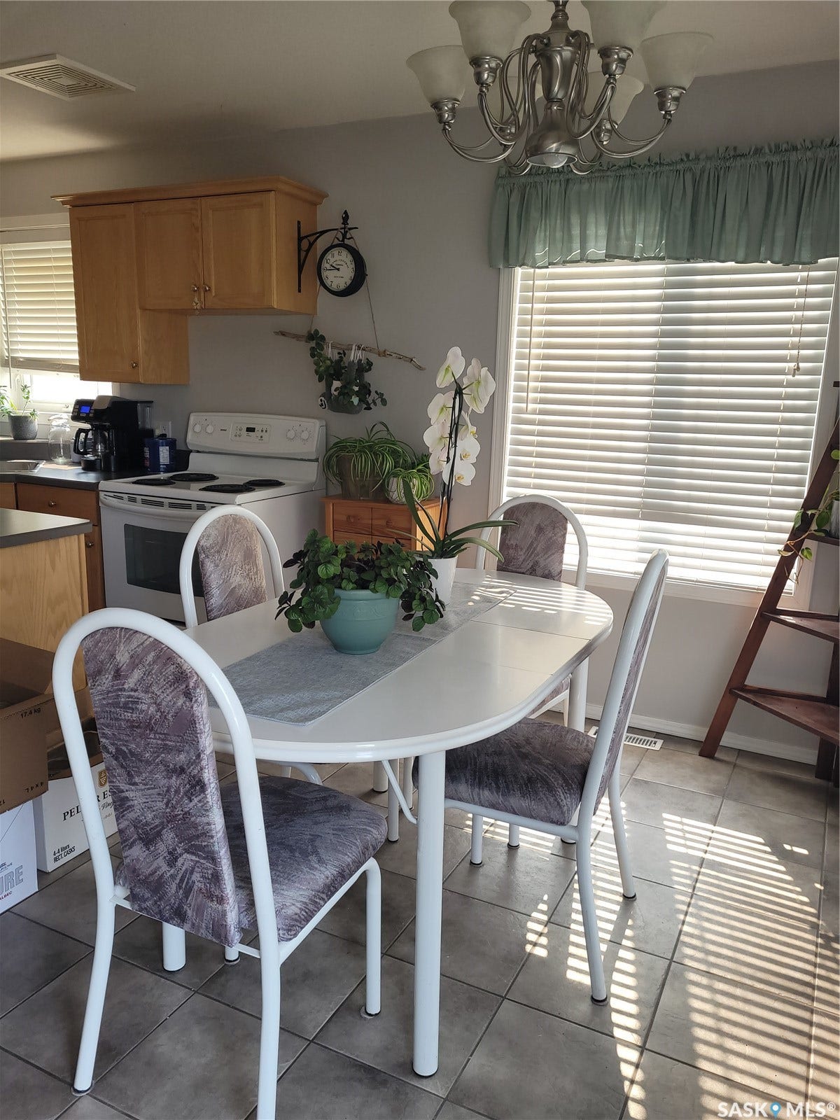 Kitchen and dining area featuring wood cabinetry, a white electric range, and tiled flooring