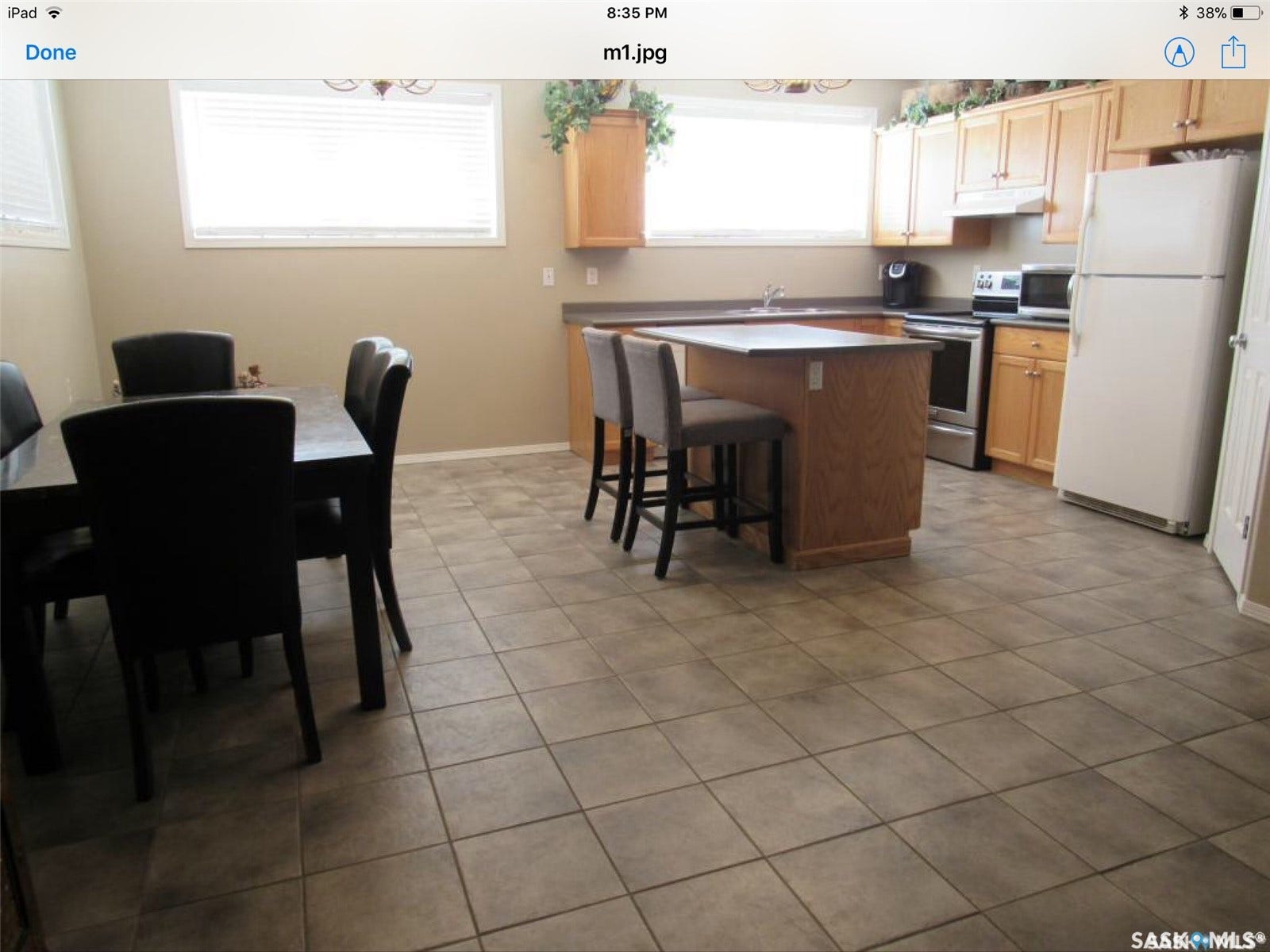 Spacious kitchen with a central island, light wood-finish cabinetry, and tiled flooring