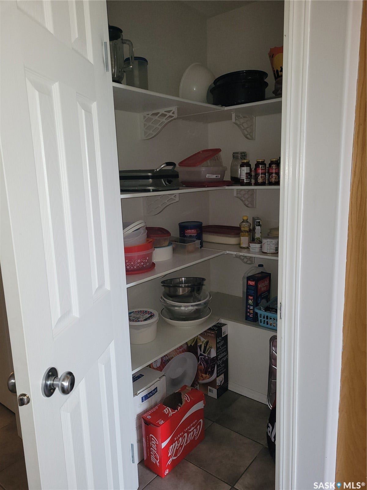 Walk-in pantry with white shelving and tiled flooring