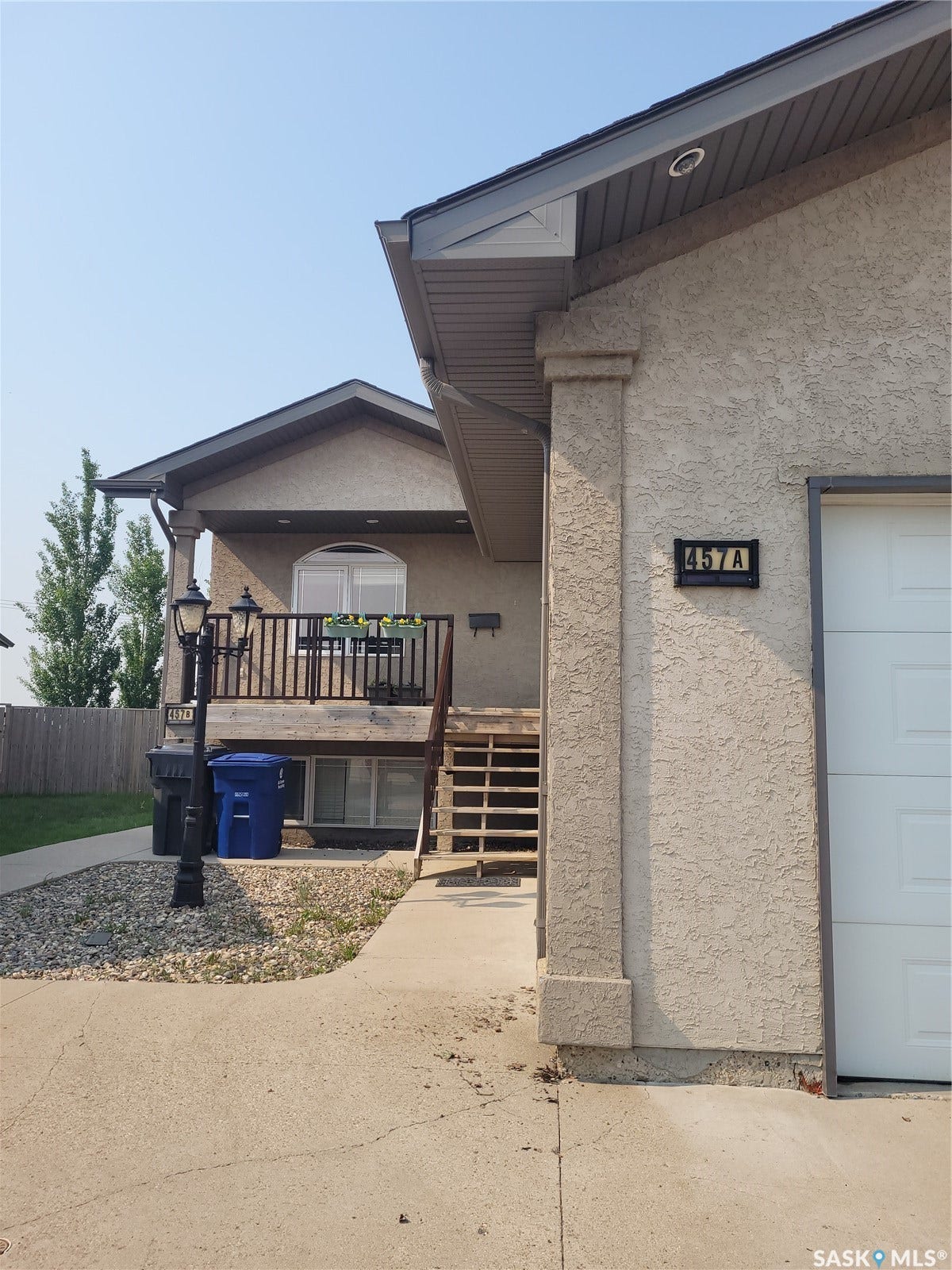 Stucco exterior with a peaked roofline, visible address numbers, and an exposed aggregate walkway