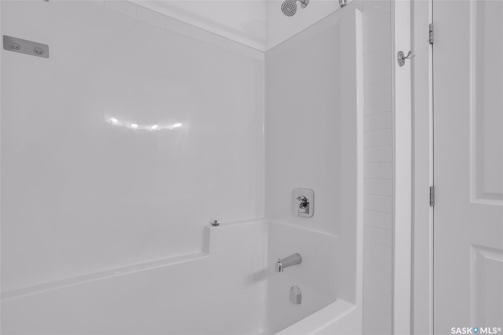 Bathtub with integrated shower, chrome fixtures, and white finish