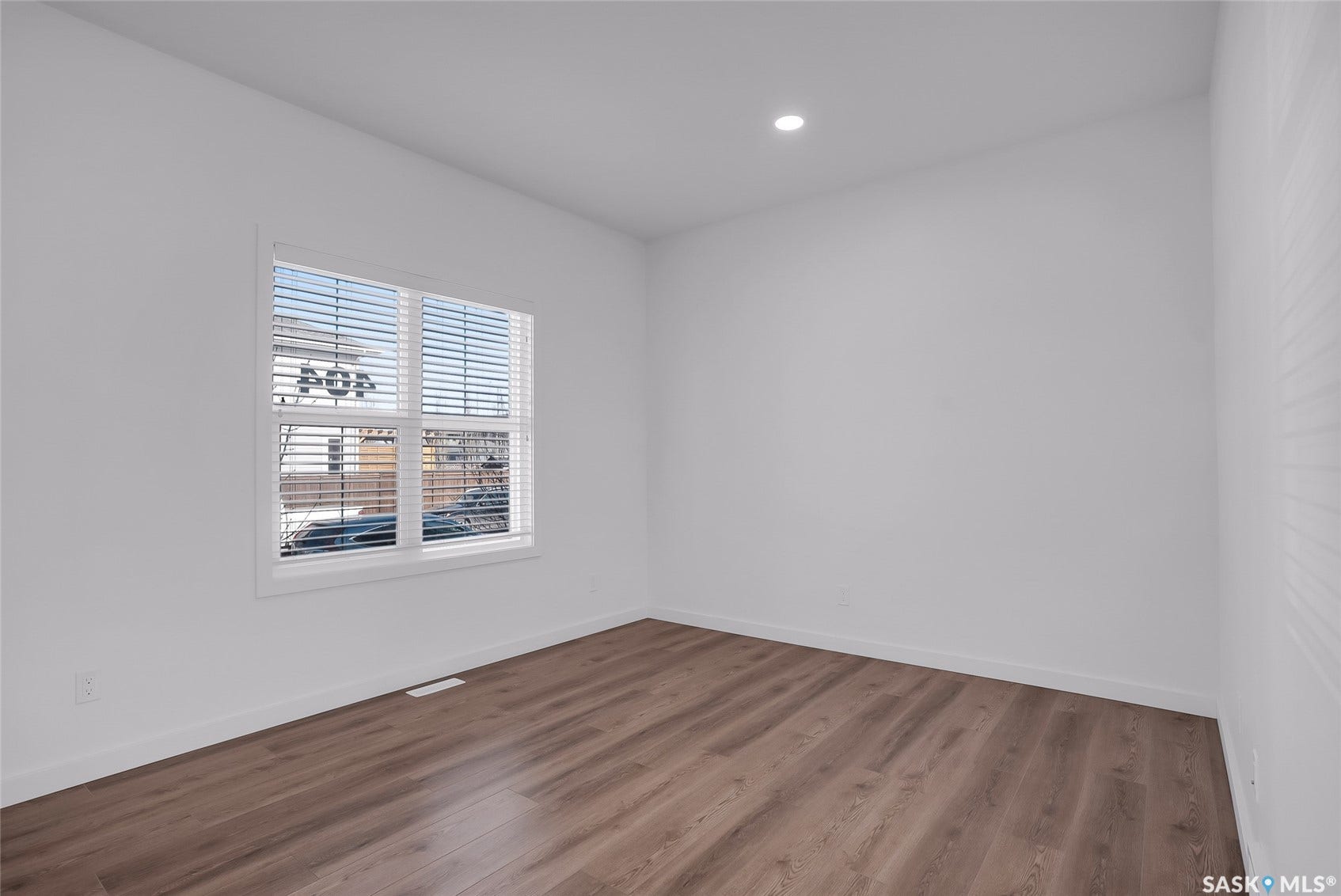 Recessed lighting, wood-finish flooring, and white walls