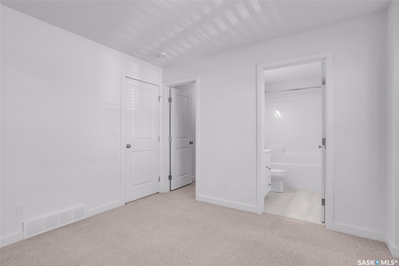 Plush carpeted flooring, white interior doors, and a bathroom featuring a white toilet, white vanity, and a tub-shower combination