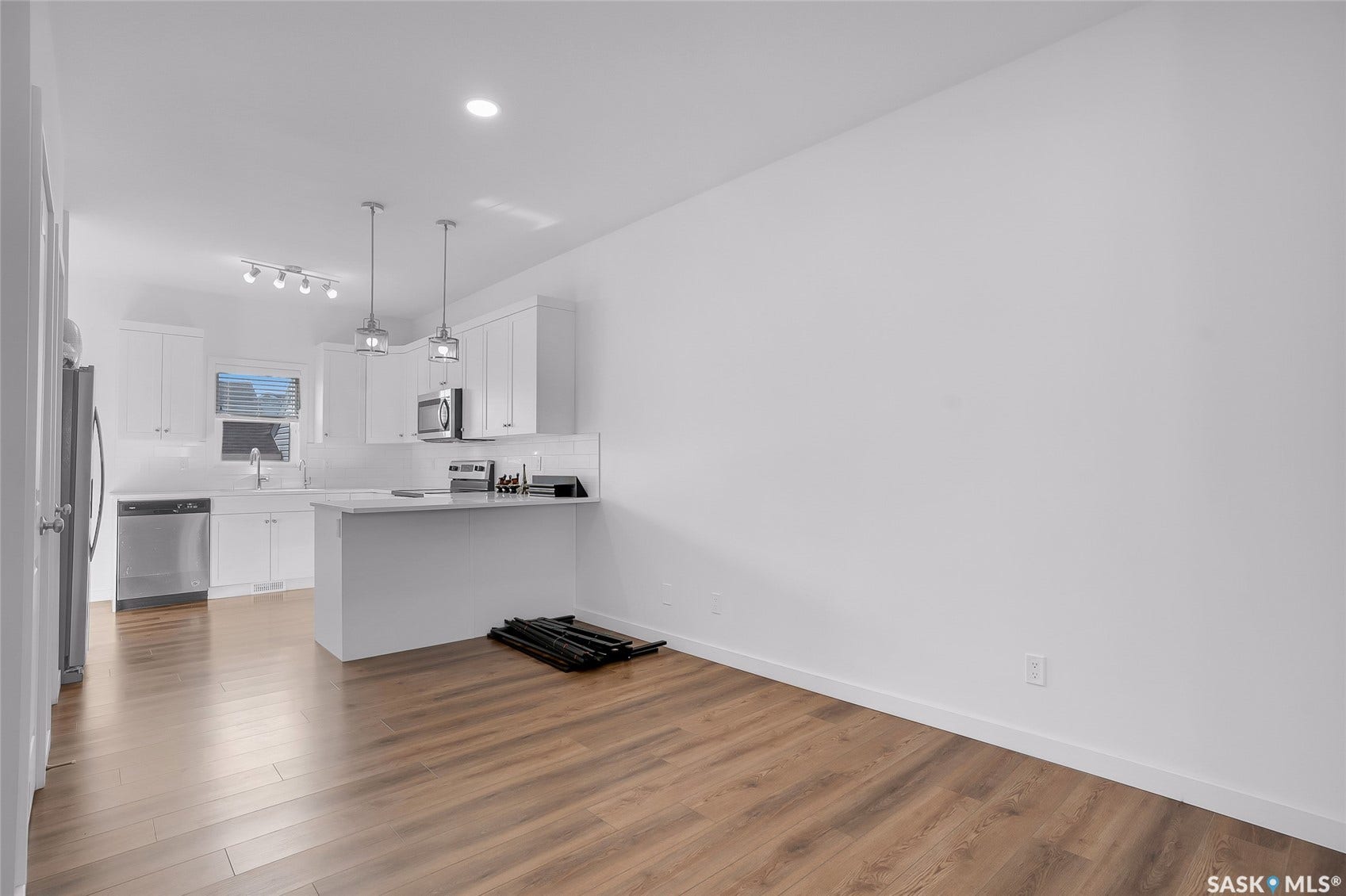 Kitchen featuring white cabinetry, stainless steel appliances, white subway tile backsplash, and a breakfast bar