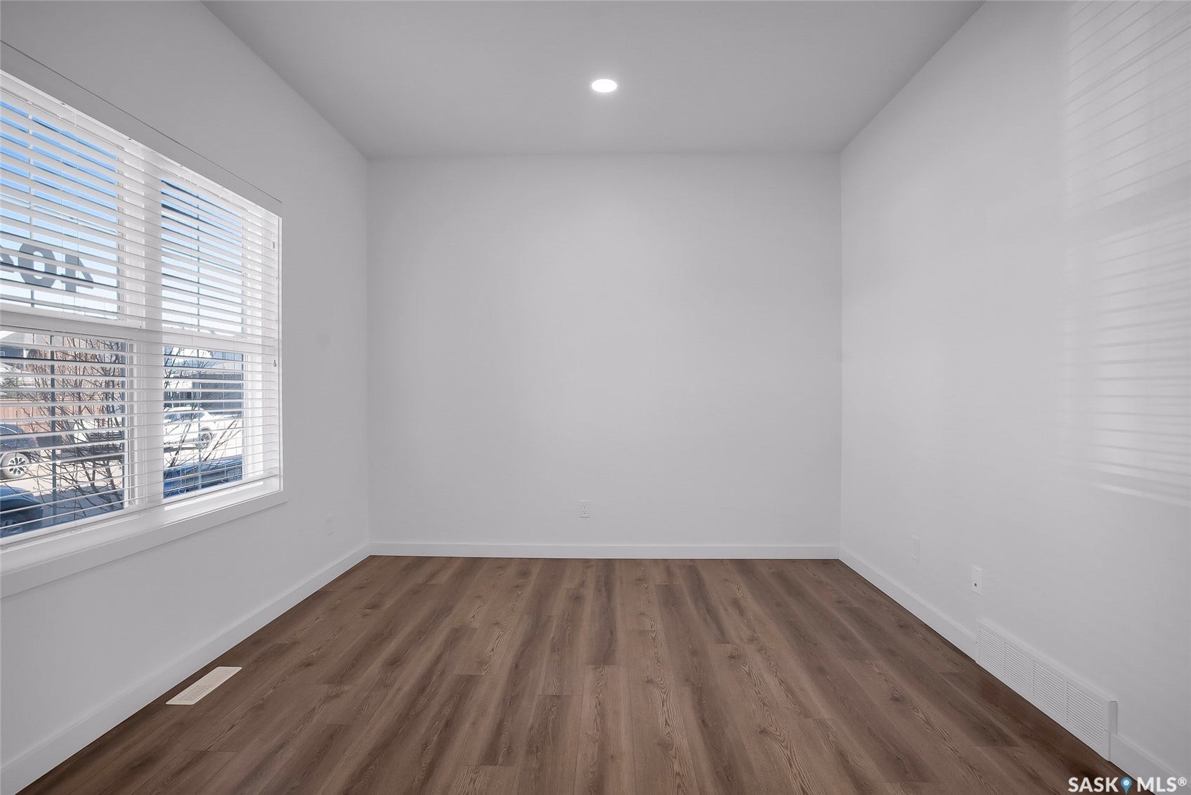 Recessed ceiling lighting, wood-finish flooring, white walls, and window with blinds