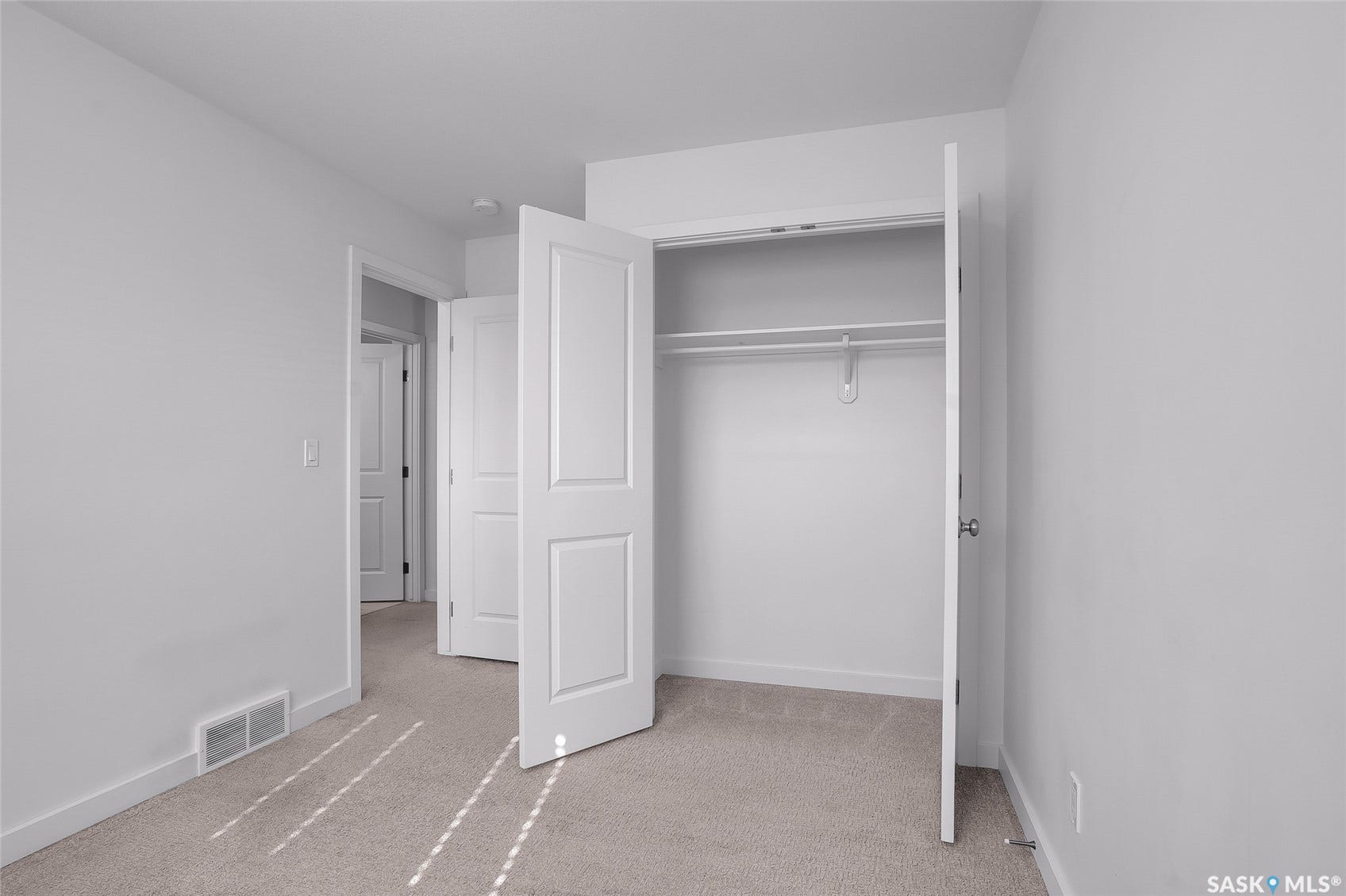 Carpeted room with a built-in closet featuring a hanging rod, white walls, and a recessed ceiling light