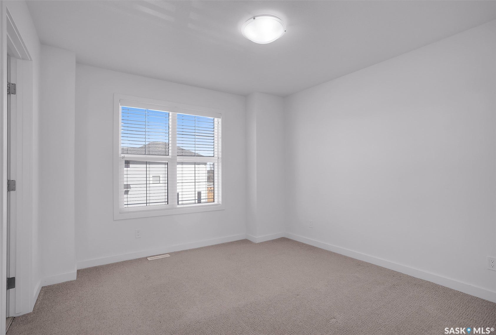 Neutral wall color, carpeted flooring, and a large window with blinds