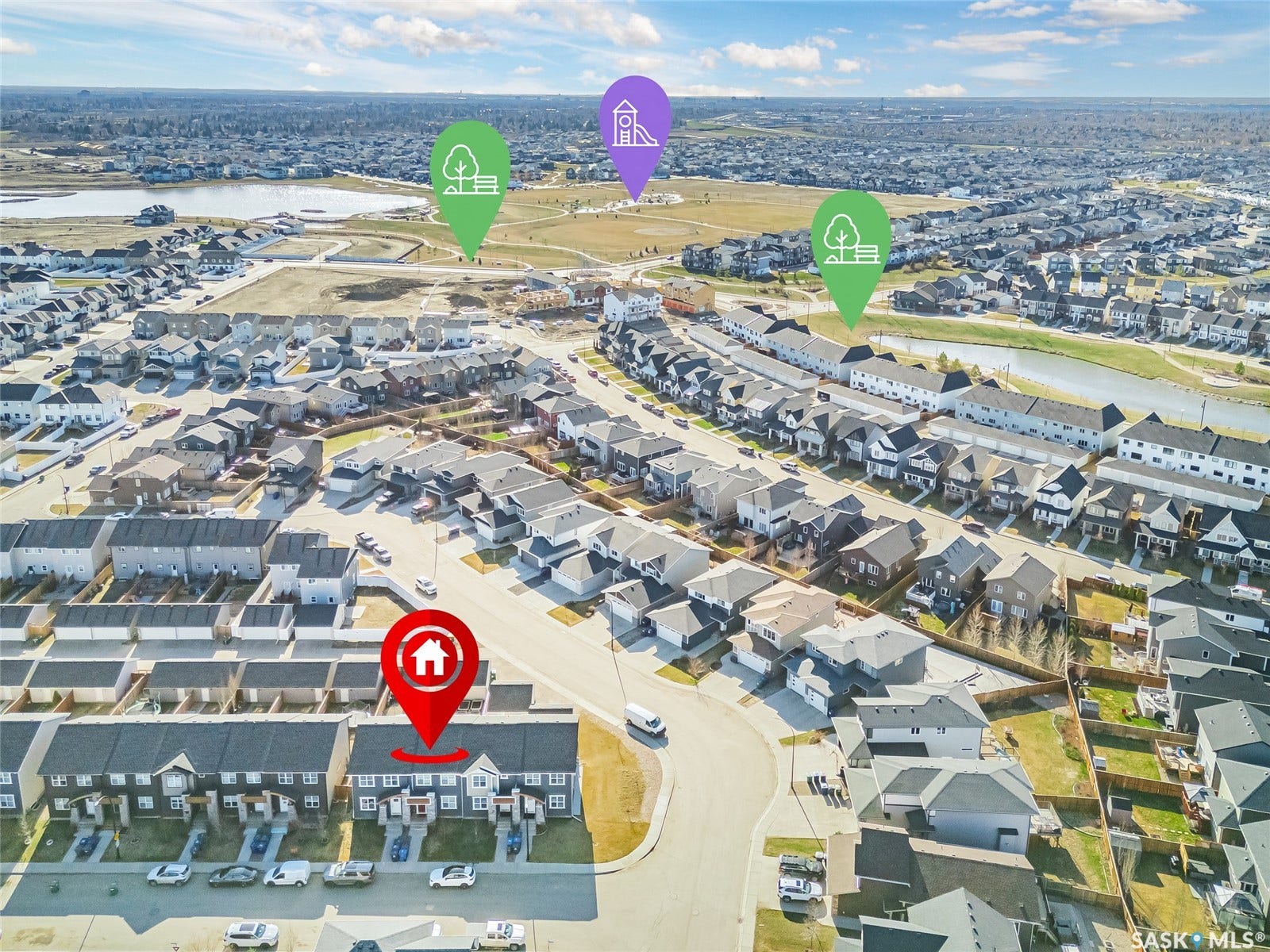 Aerial view of a residential community featuring townhomes and detached houses, surrounded by green spaces and a water feature