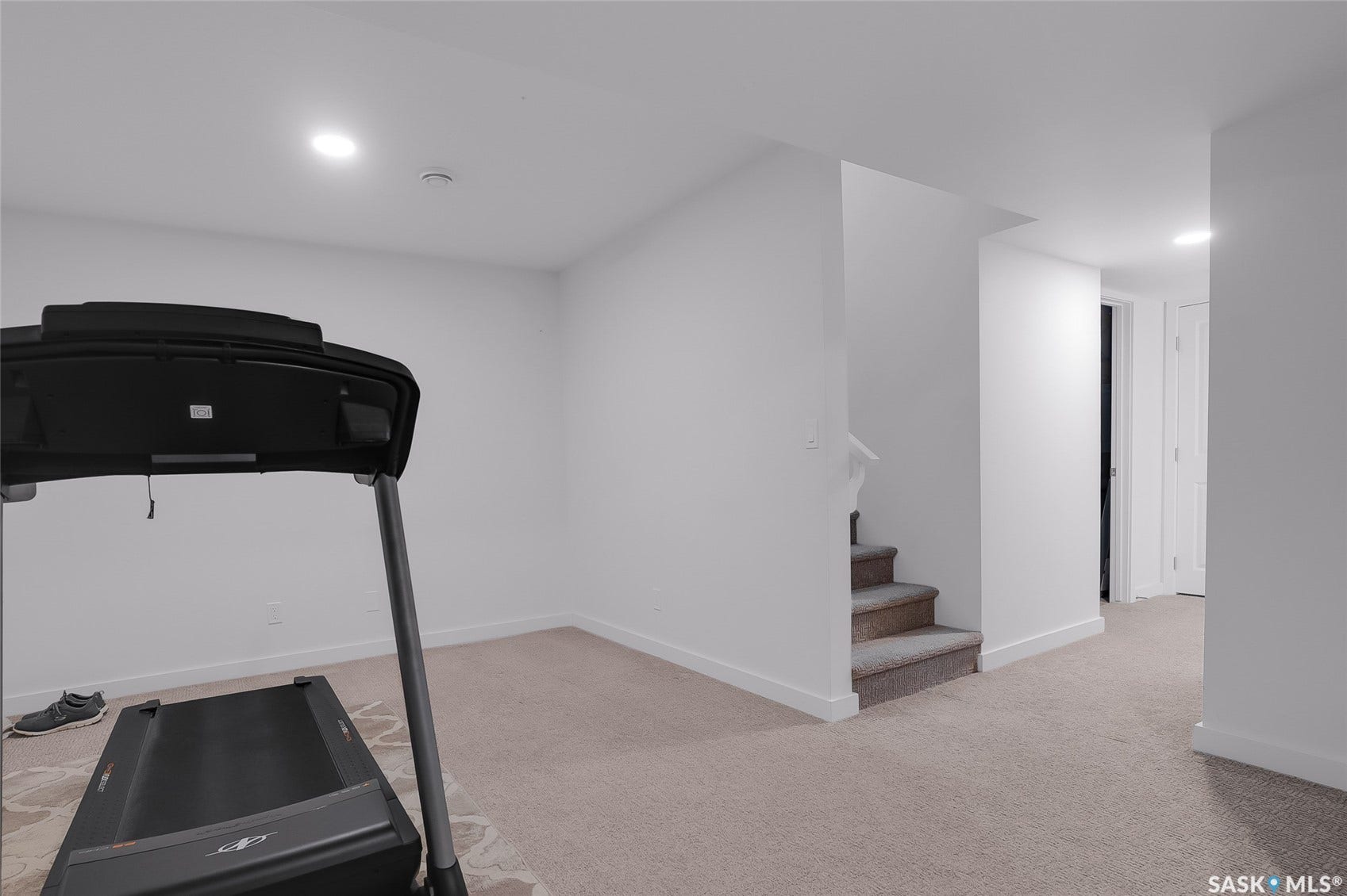 Carpeted room with recessed lighting and a carpeted staircase