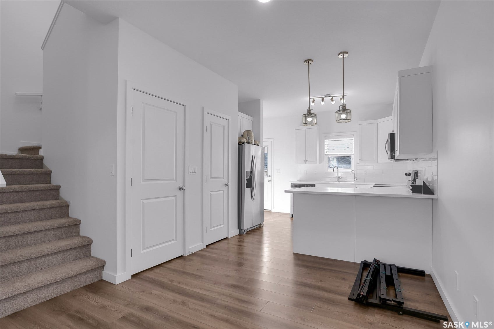 Contemporary kitchen with white cabinetry, stainless steel appliances, white subway tile backsplash, and two pendant light fixtures