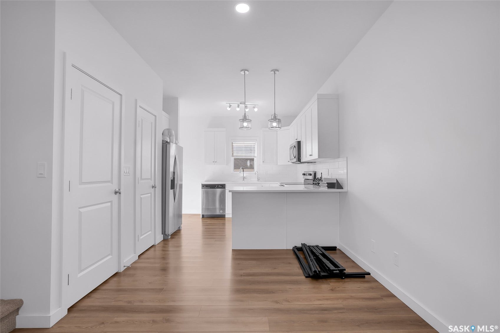 Wood-finish flooring throughout, bright white walls, and a recessed ceiling light