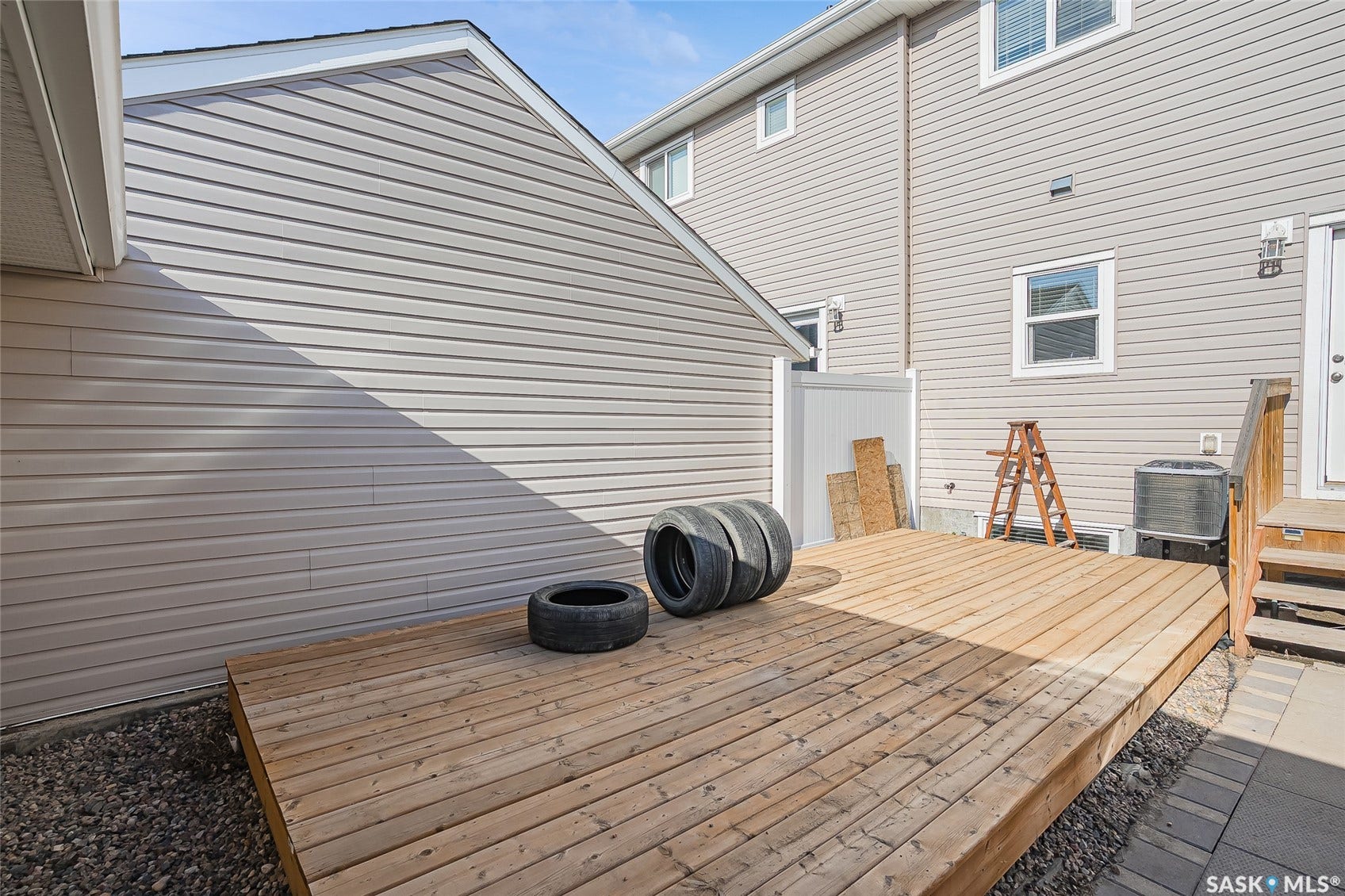 Expansive wood deck with stairs, flanked by gravel and paver landscaping