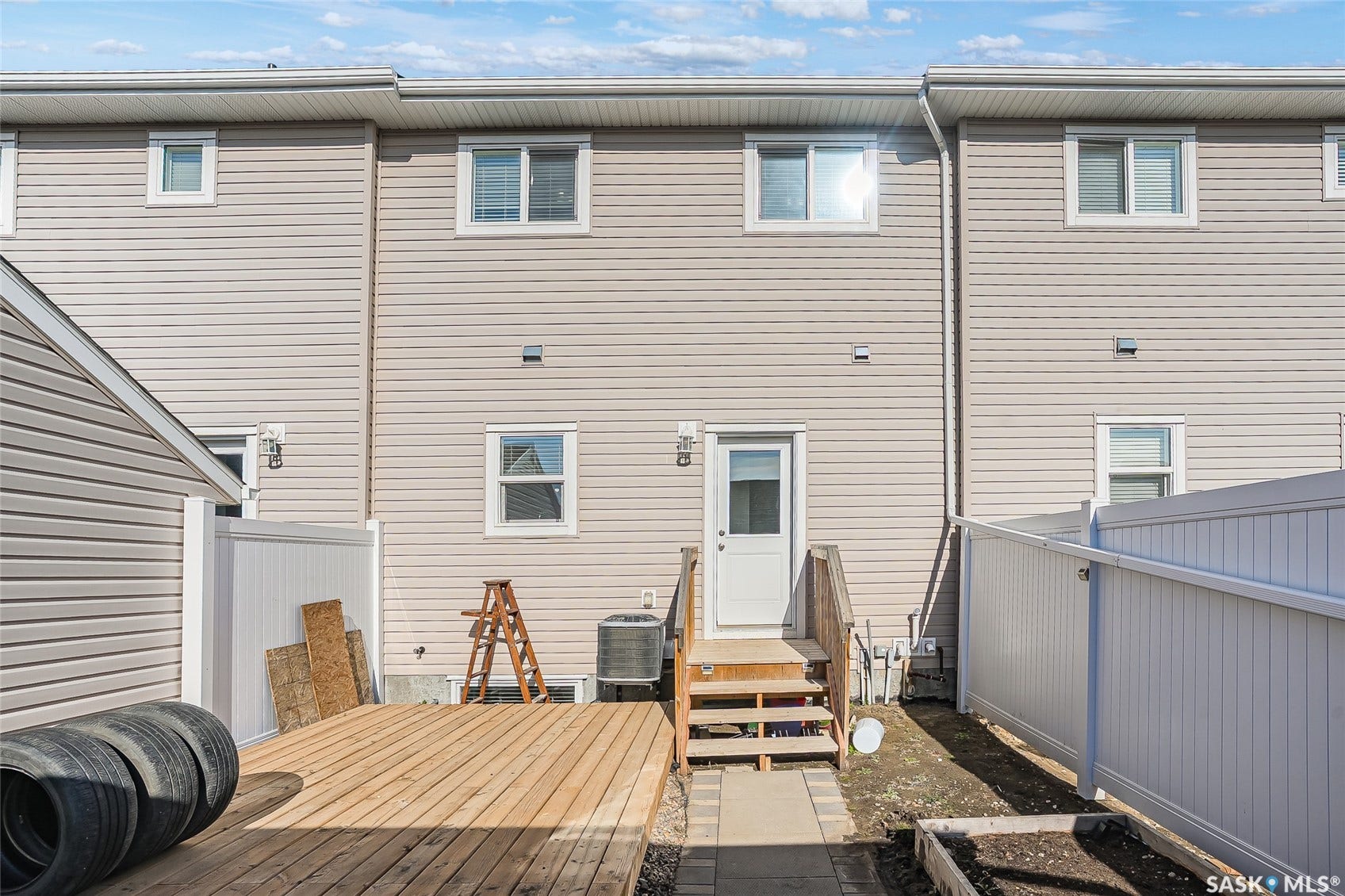 Rear exterior featuring light-colored horizontal siding, white-framed windows, and a wooden deck with stairs