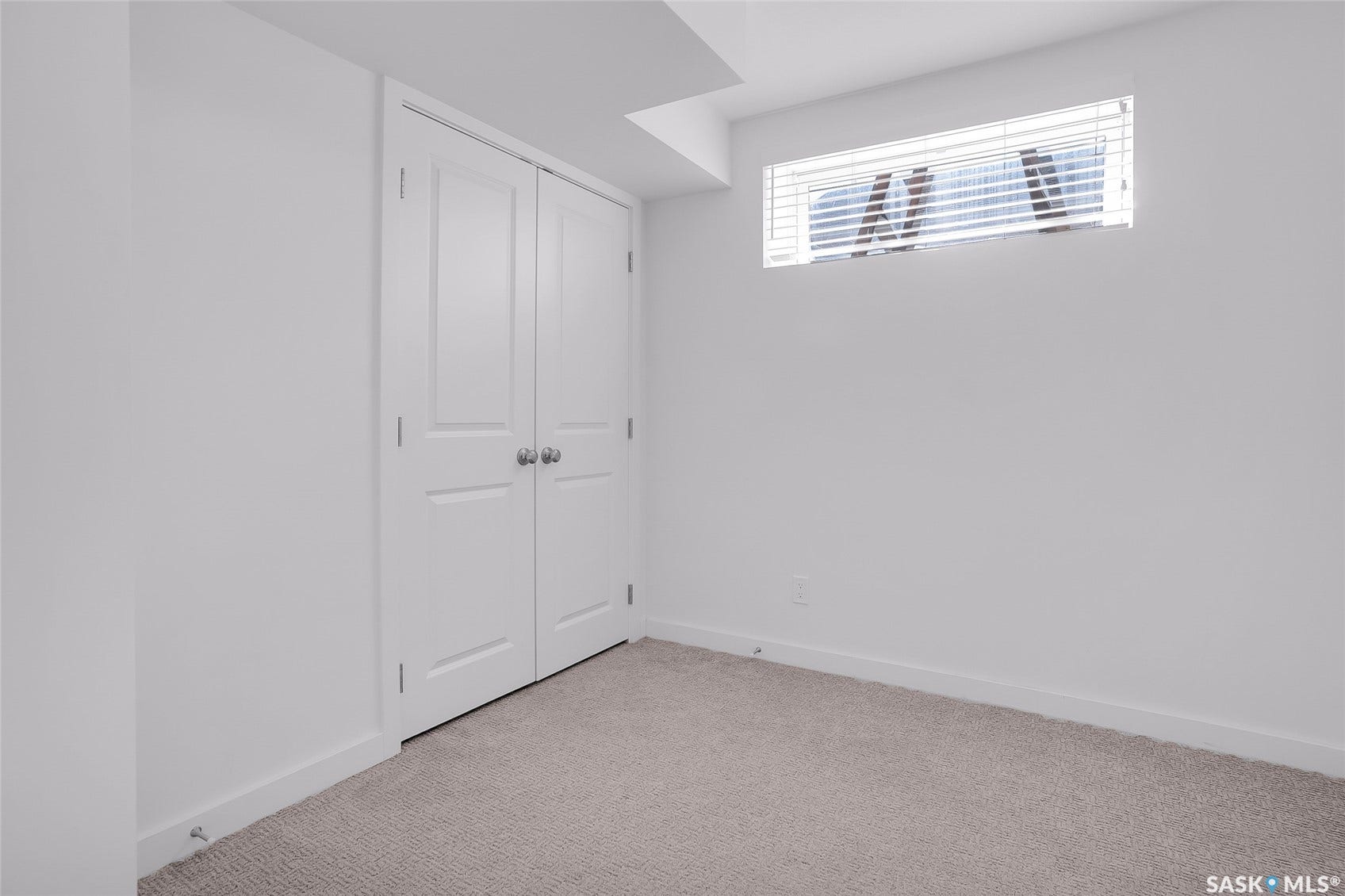 Carpeted flooring, white walls, and a window with blinds