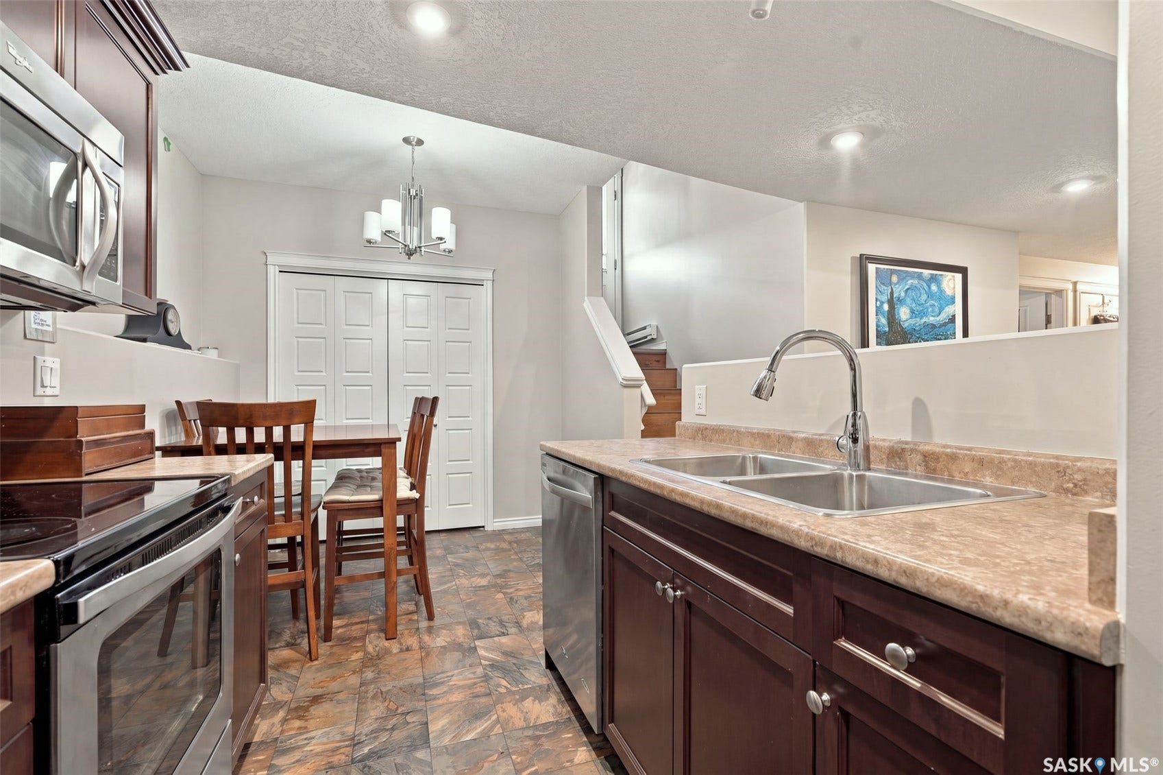919 Kolynchuk Bend, Saskatoon SK S7T 0V9 Dark wood-finish cabinetry, stainless steel appliances, dual basin sink, wood-finish flooring, and recessed lighting