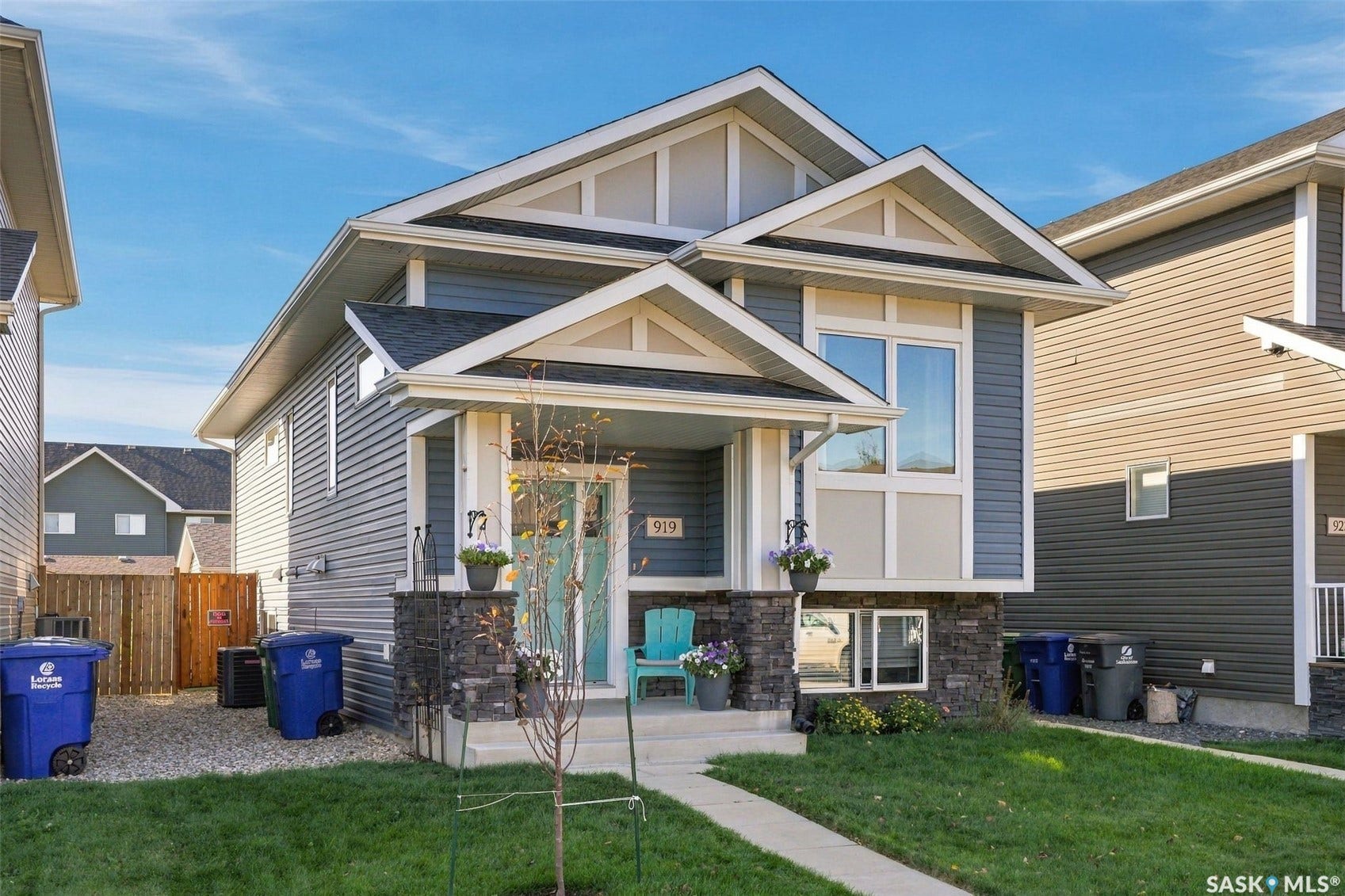 919 Kolynchuk Bend, Saskatoon SK S7T 0V9 Modern residential exterior with a covered front porch, stone detailing, and an integrated garage