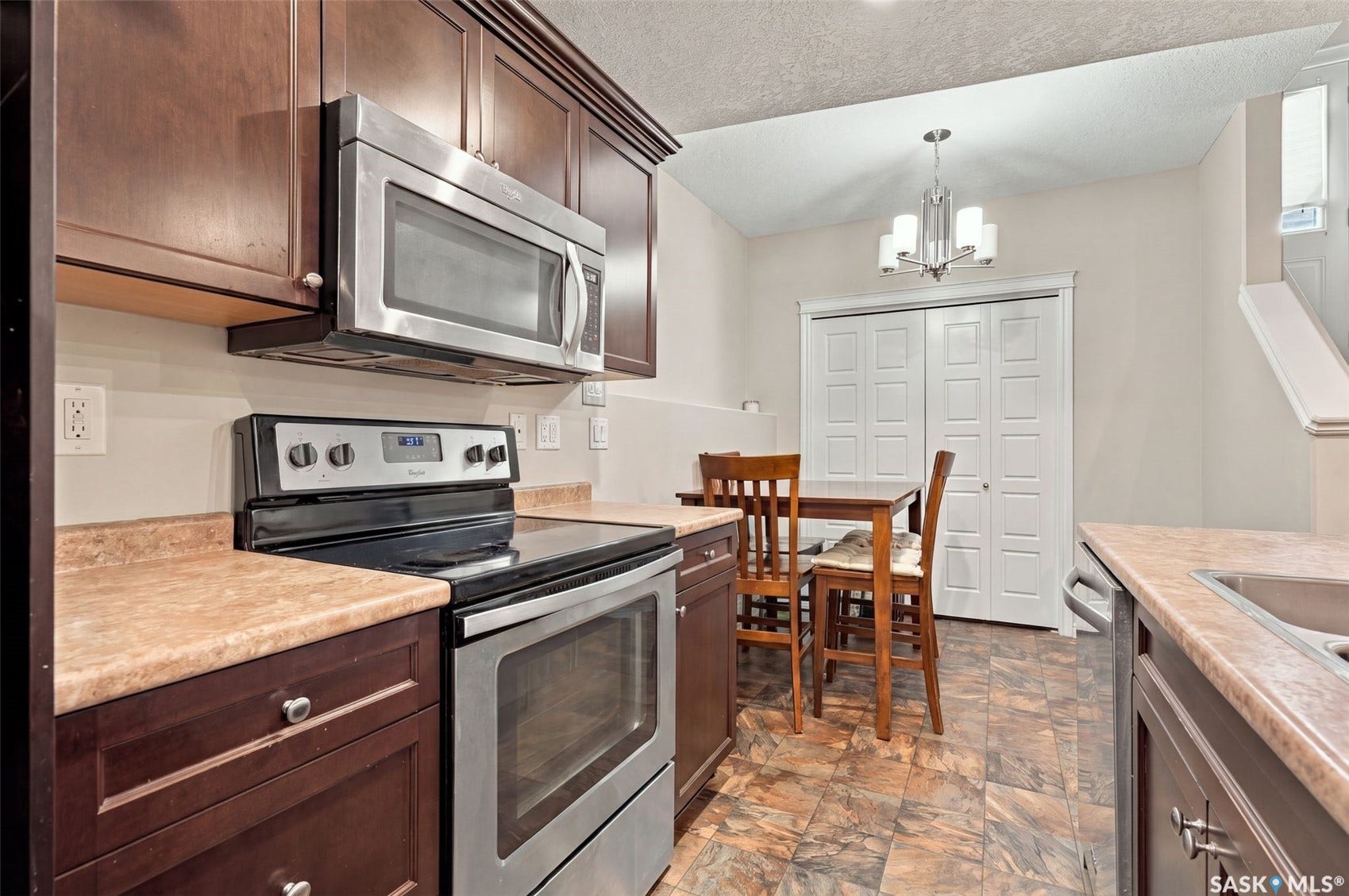 919 Kolynchuk Bend, Saskatoon SK S7T 0V9 Rich wood-finish cabinetry, stainless steel appliances, and a built-in kitchen sink