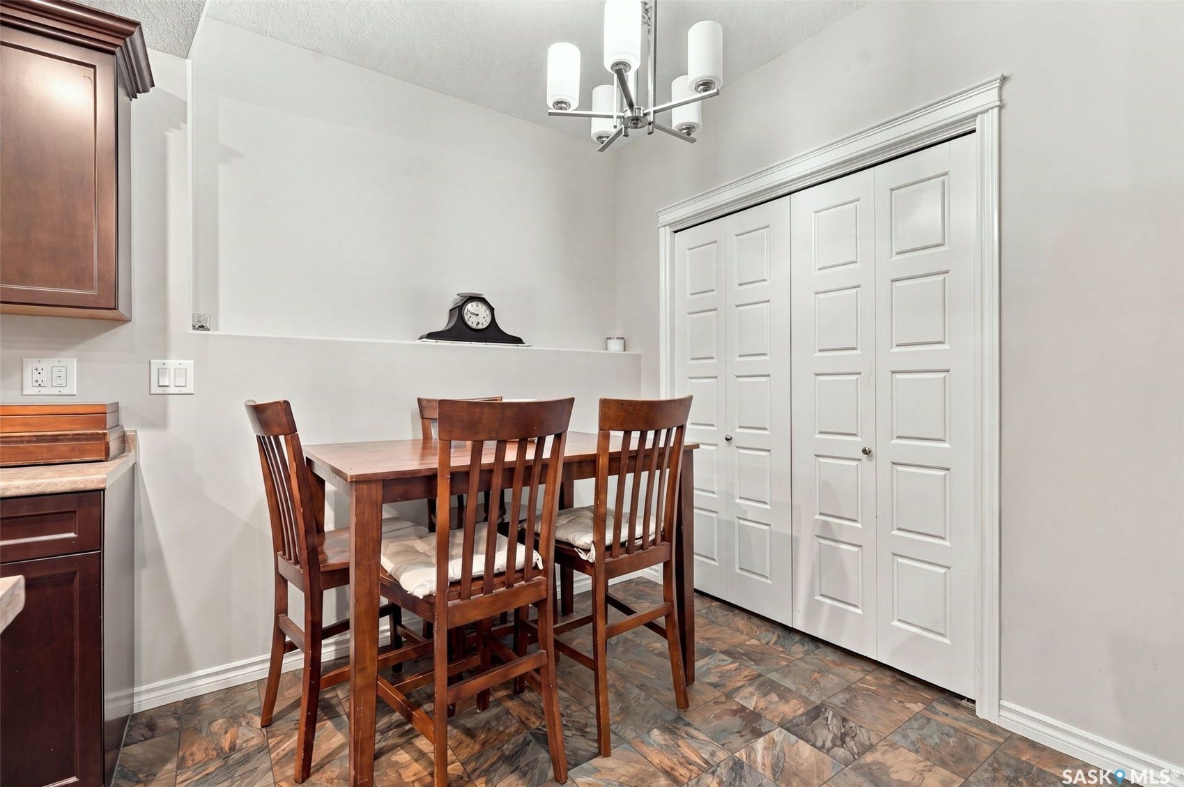 919 Kolynchuk Bend, Saskatoon SK S7T 0V9 Built-in shelving, white bi-fold closet doors, overhead lighting fixture, wood-finish flooring, and dark wood-finish cabinetry