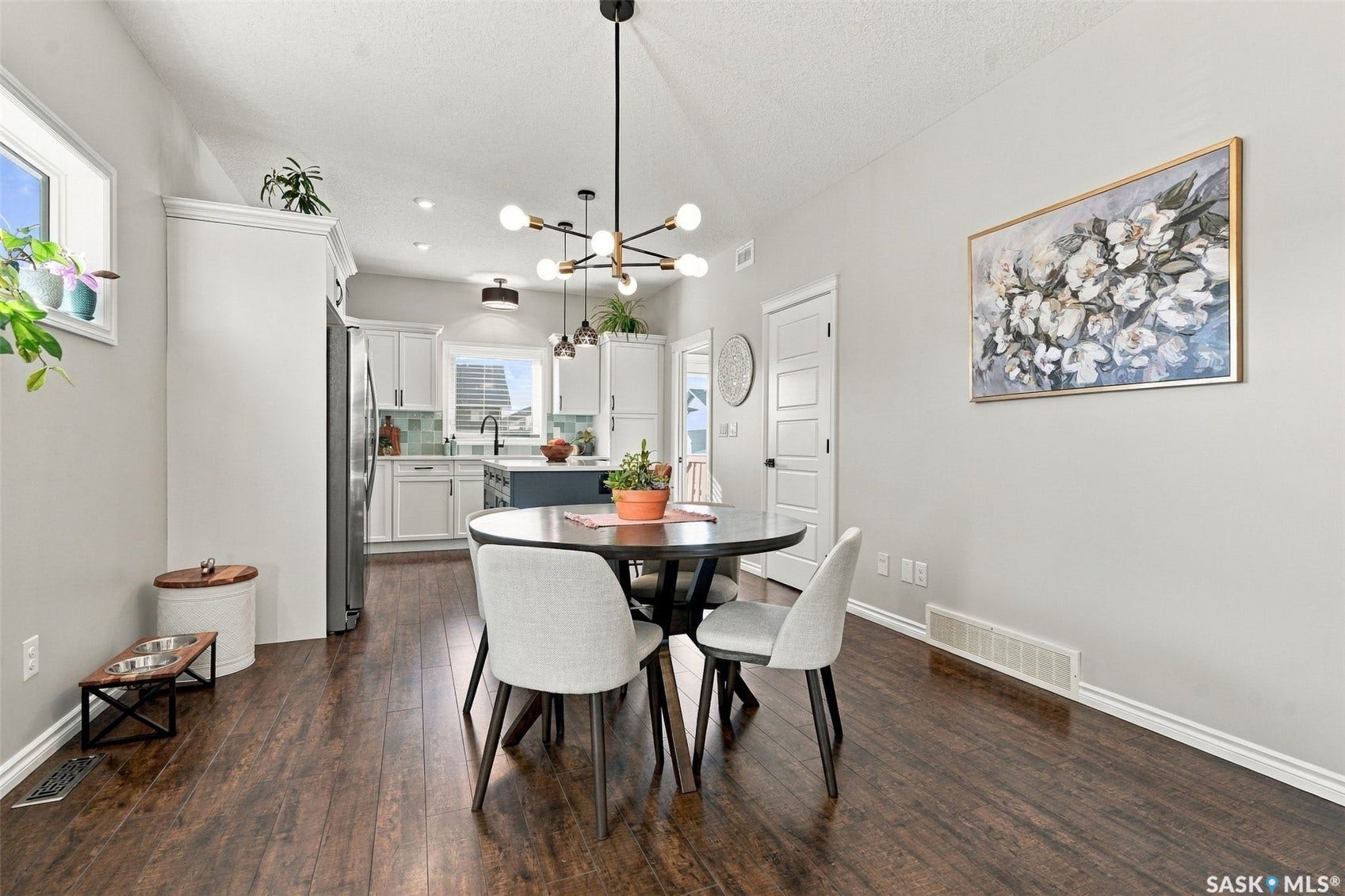 919 Kolynchuk Bend, Saskatoon SK S7T 0V9 Vaulted ceiling with an exposed beam, wood-finish flooring, white kitchen cabinetry, and a kitchen island with a dark countertop