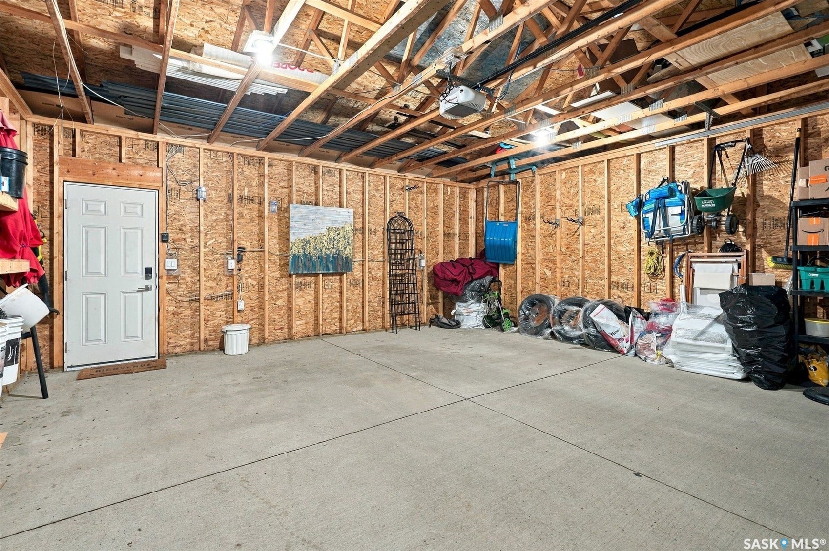 919 Kolynchuk Bend, Saskatoon SK S7T 0V9 Concrete flooring, exposed wood framing, overhead lighting, interior access door, garage door opener mechanism