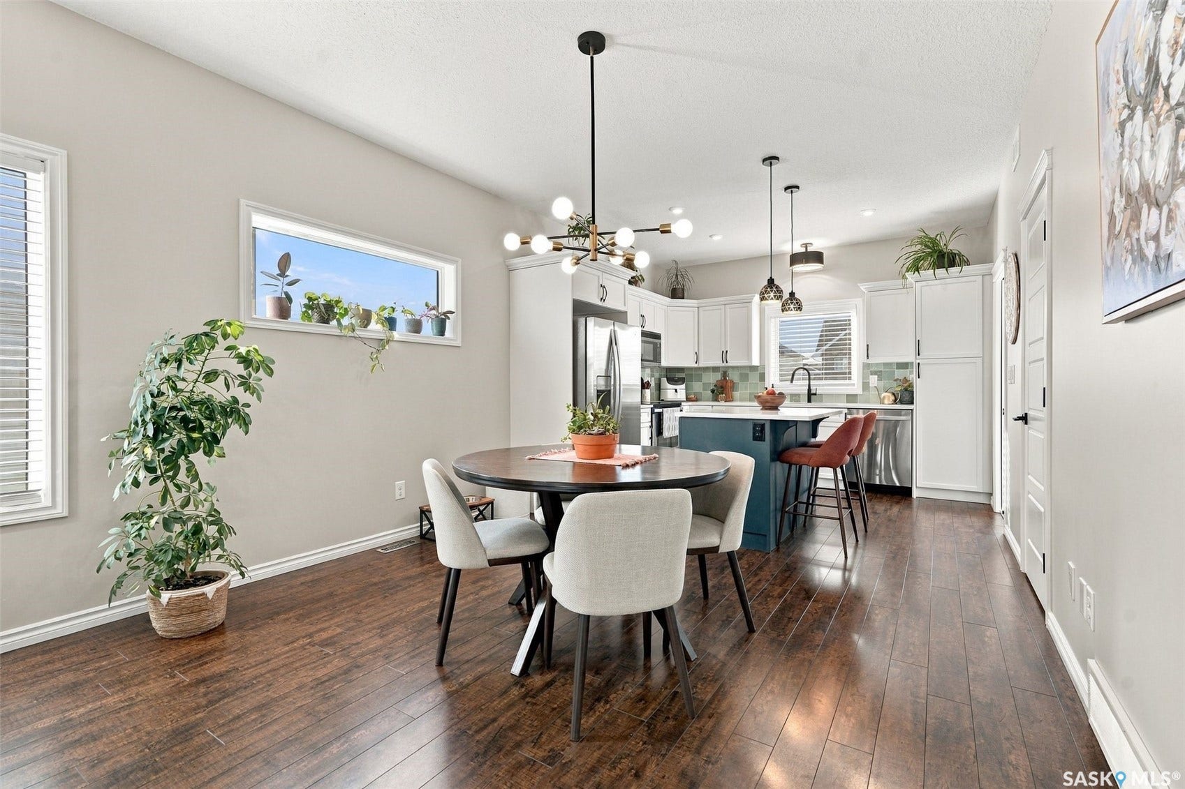 919 Kolynchuk Bend, Saskatoon SK S7T 0V9 Wood-finish flooring, contemporary lighting, white cabinetry, island with integrated seating, and stainless steel appliances
