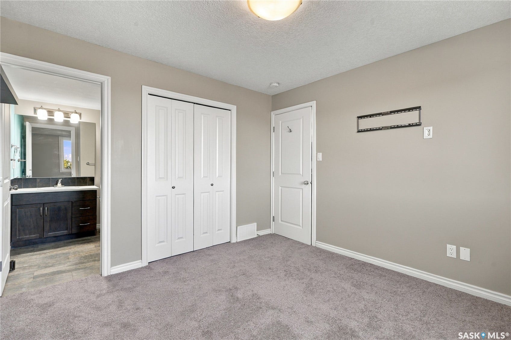 Plush grey carpeting, white bi-fold closet doors, and light grey wall finishes