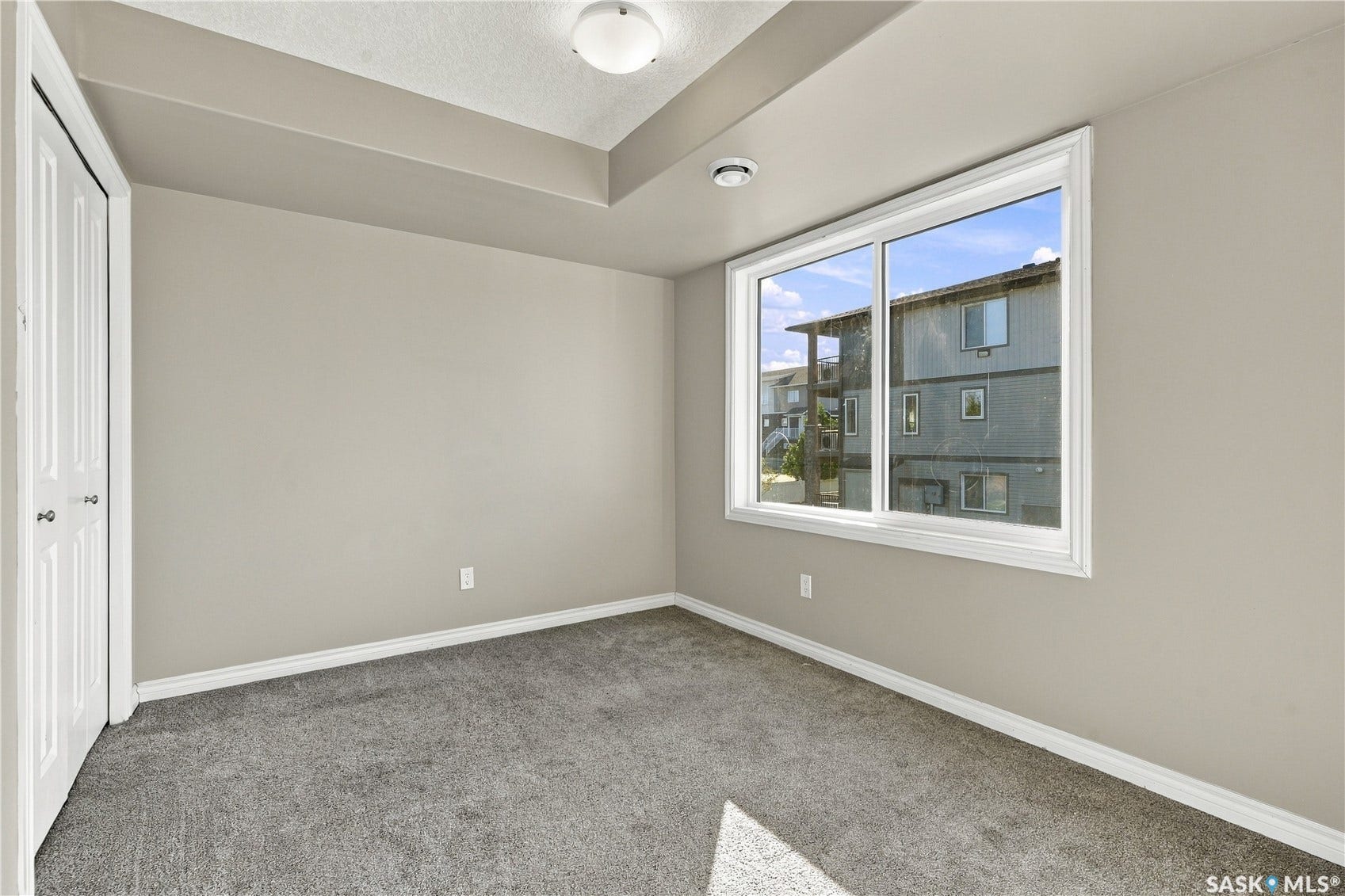 Recessed ceiling, neutral wall paint, white trim, carpeted flooring, and a double-pane window