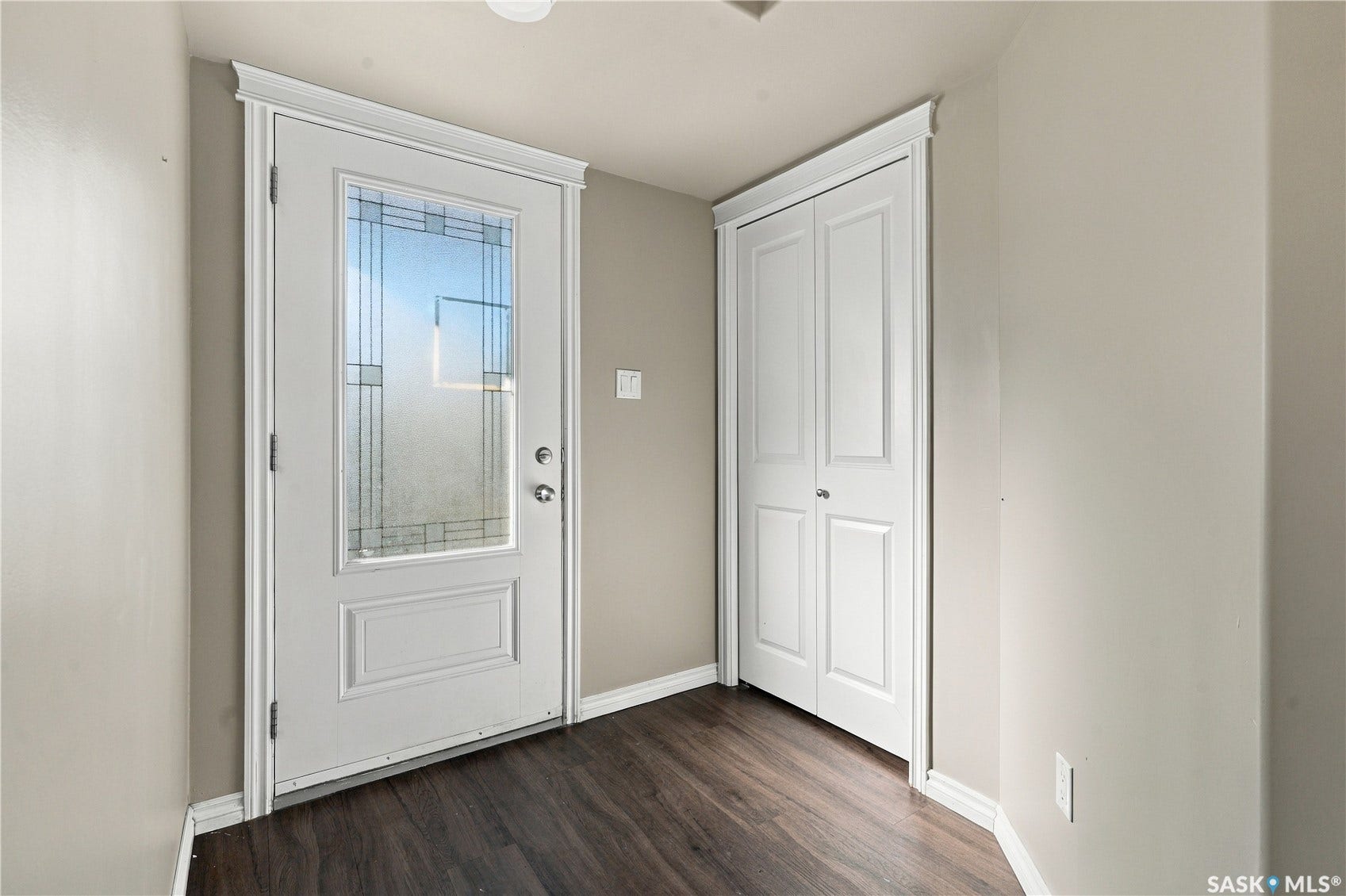Entryway featuring a white door with decorative glass, a bi-fold closet, and laminate flooring