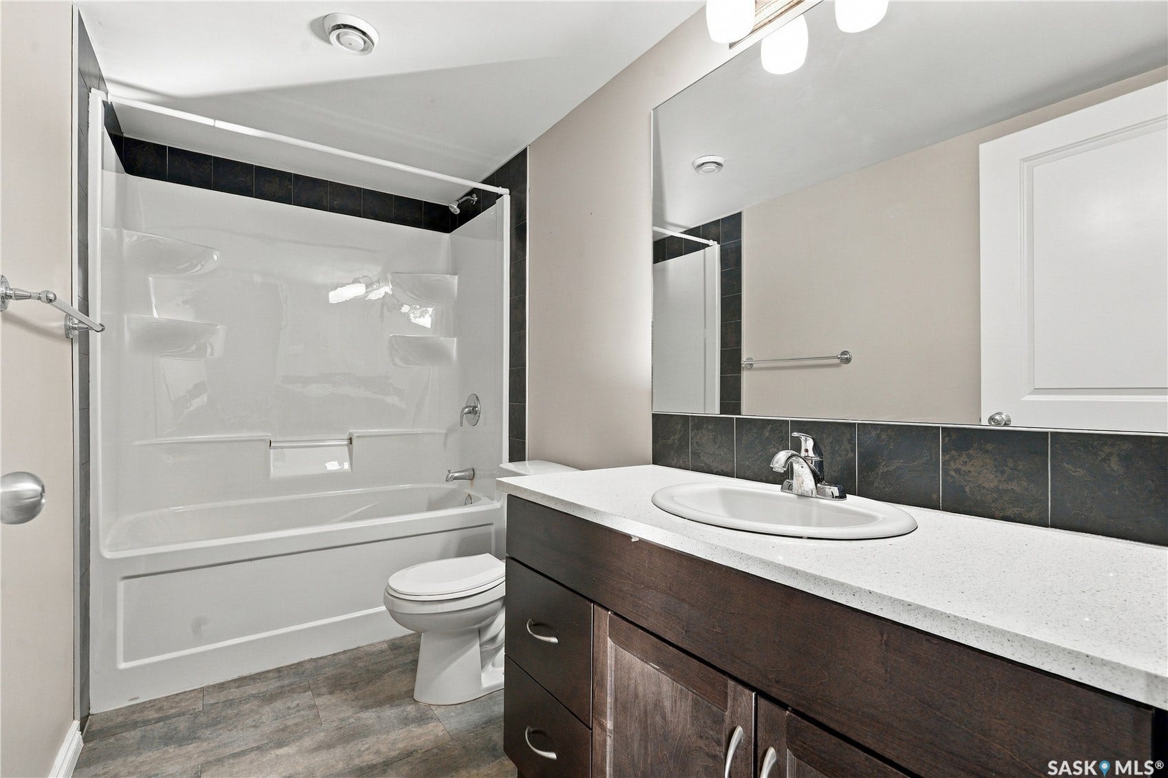 4 piece main bathroom with a dark wood-finish vanity, a white quartz countertop, and integrated sink