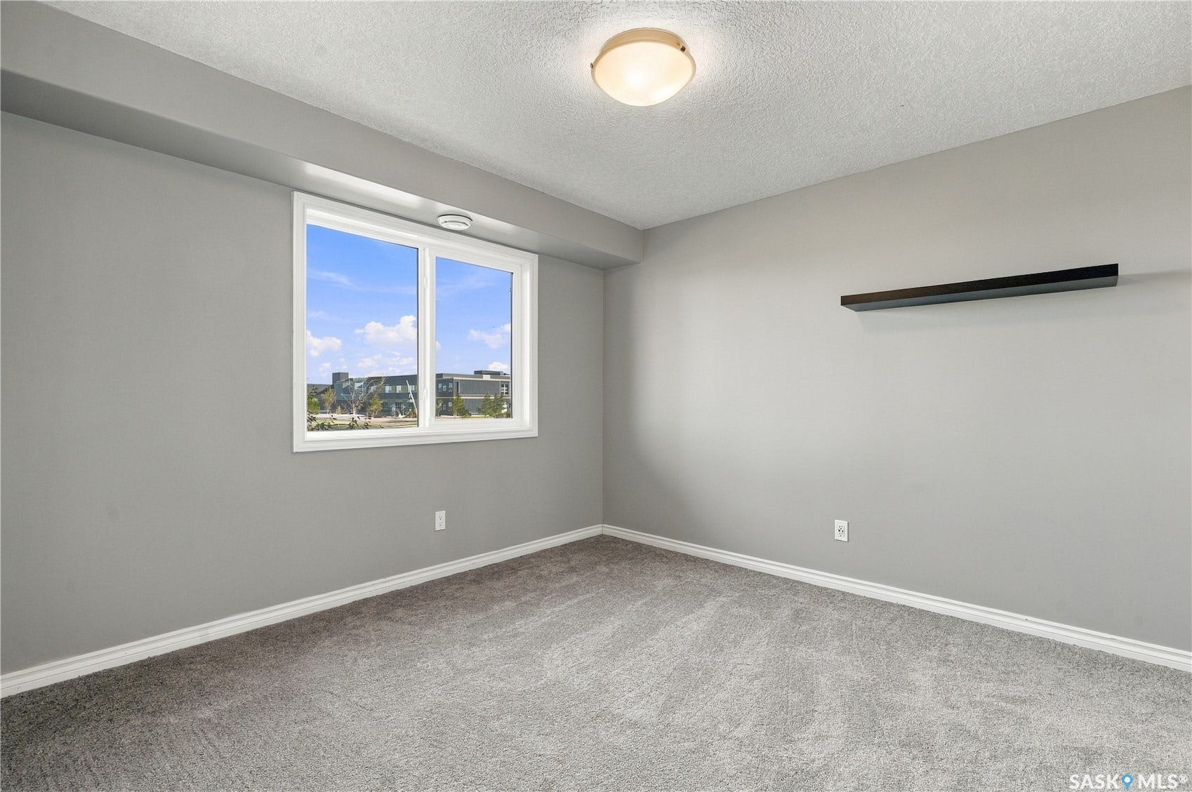 New carpeting, neutral wall color, built-in wall shelf, flush-mount ceiling light, and large window