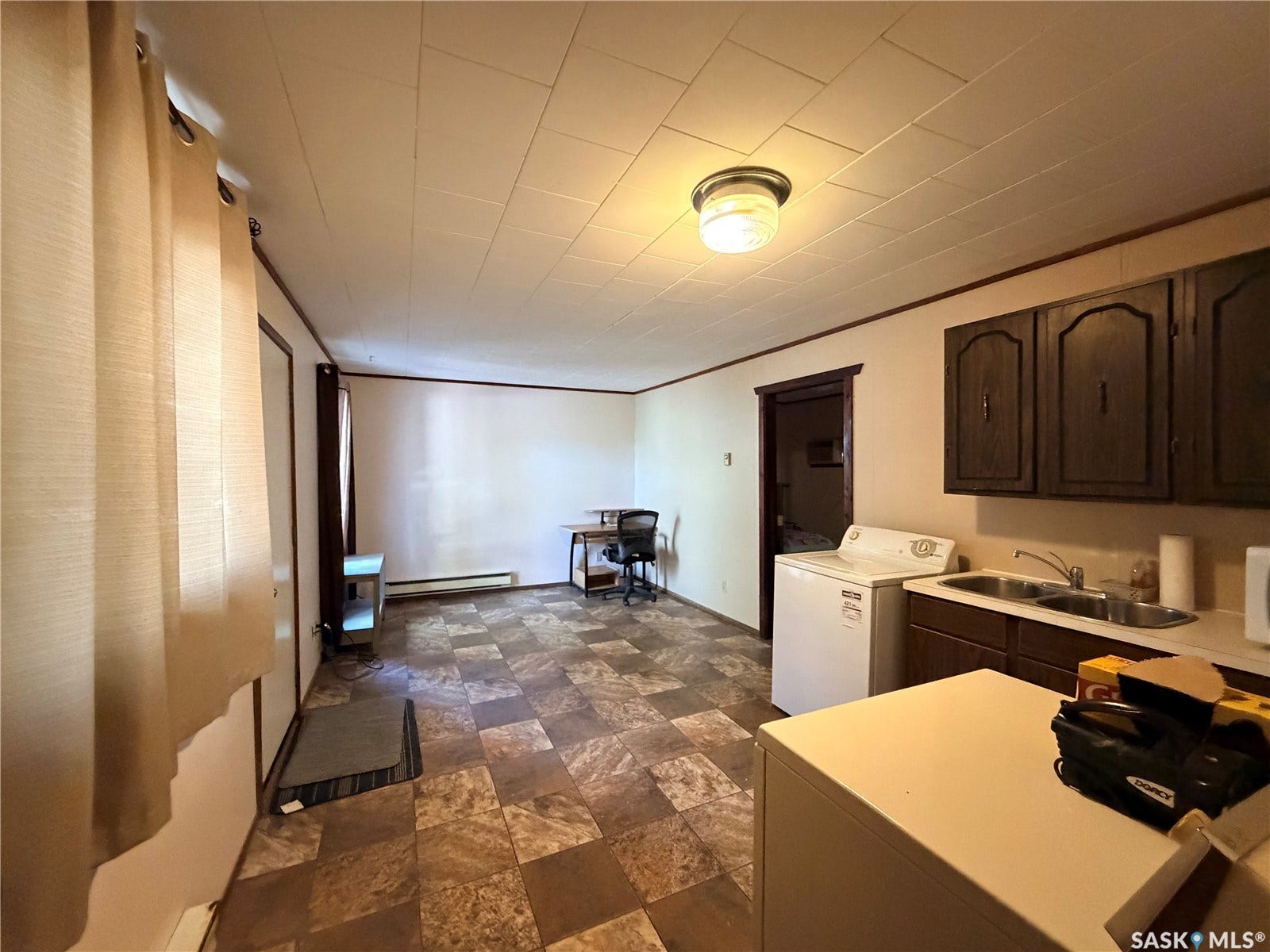 Kitchenette with wood-finish cabinetry, double-basin stainless steel sink, and light-toned countertop