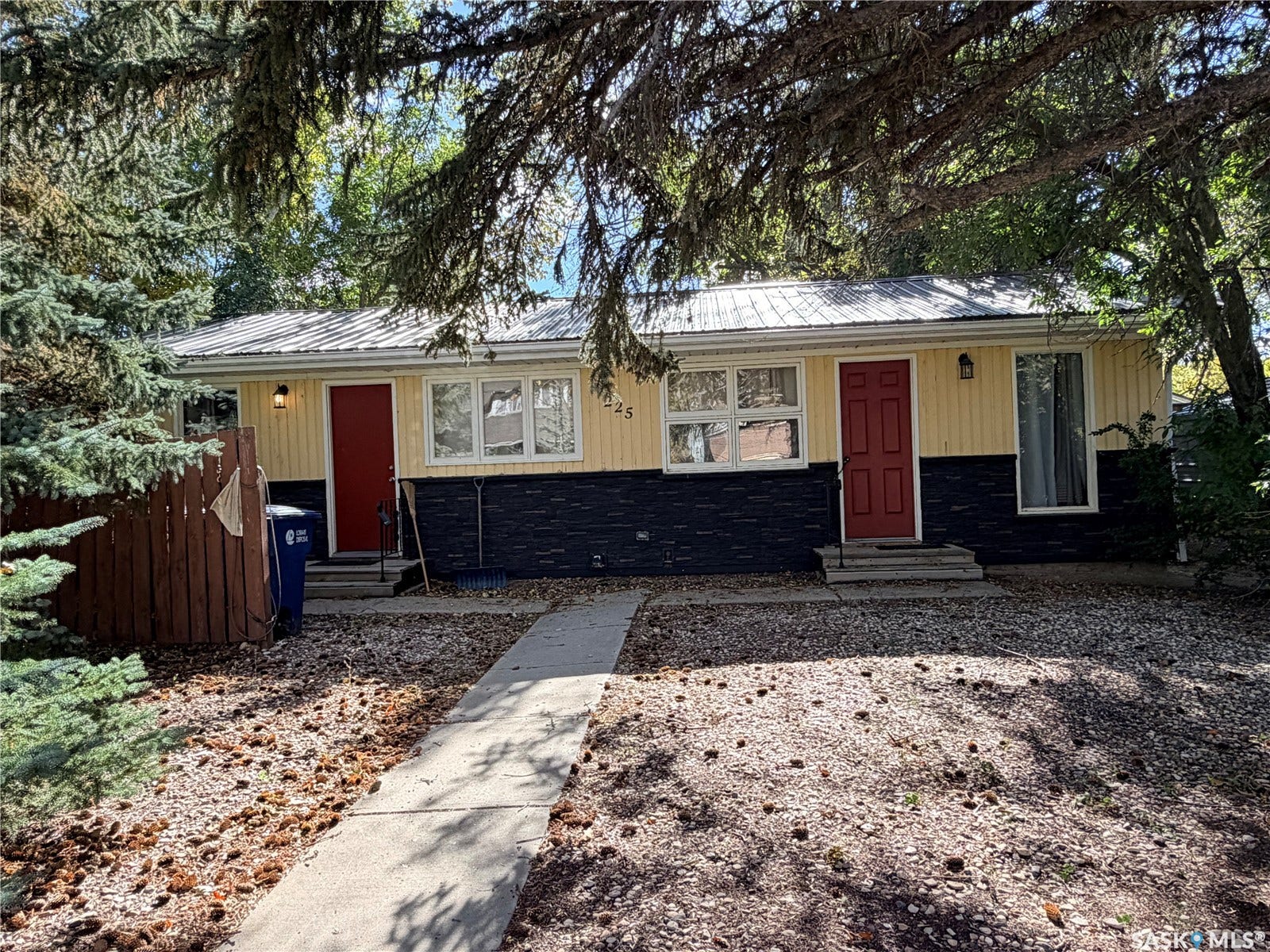 Yellow siding exterior with a metal roof and two red entry doors