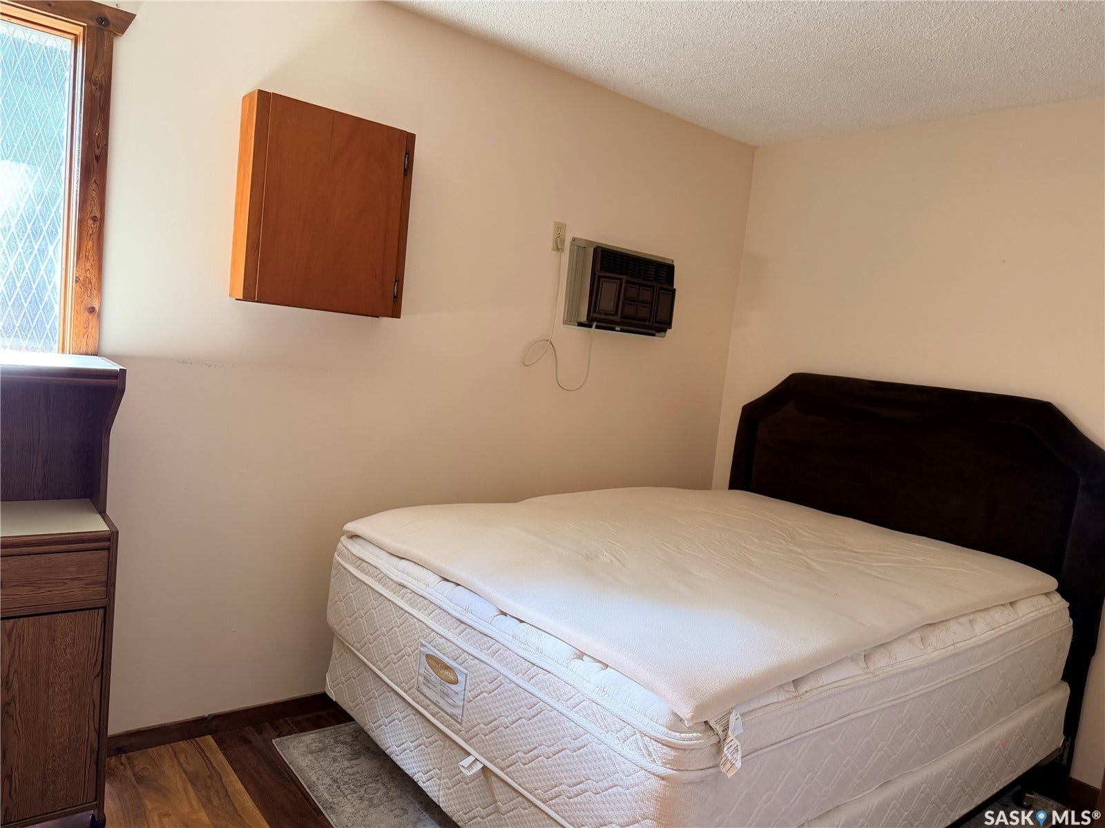 Window with diamond-patterned mullions, wood-finish flooring, and a wall-mounted cabinet