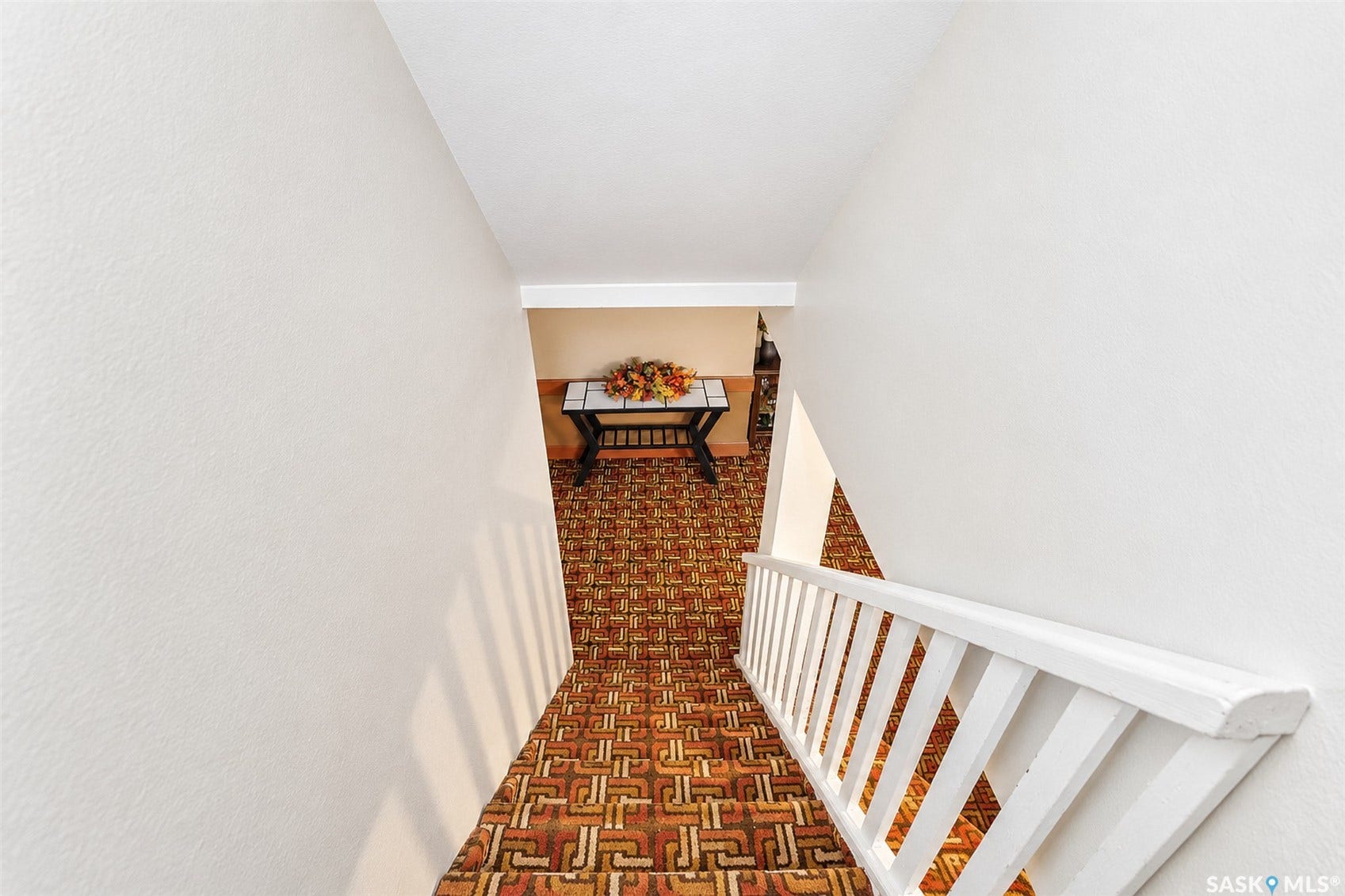Staircase featuring a patterned carpet runner and white painted handrails