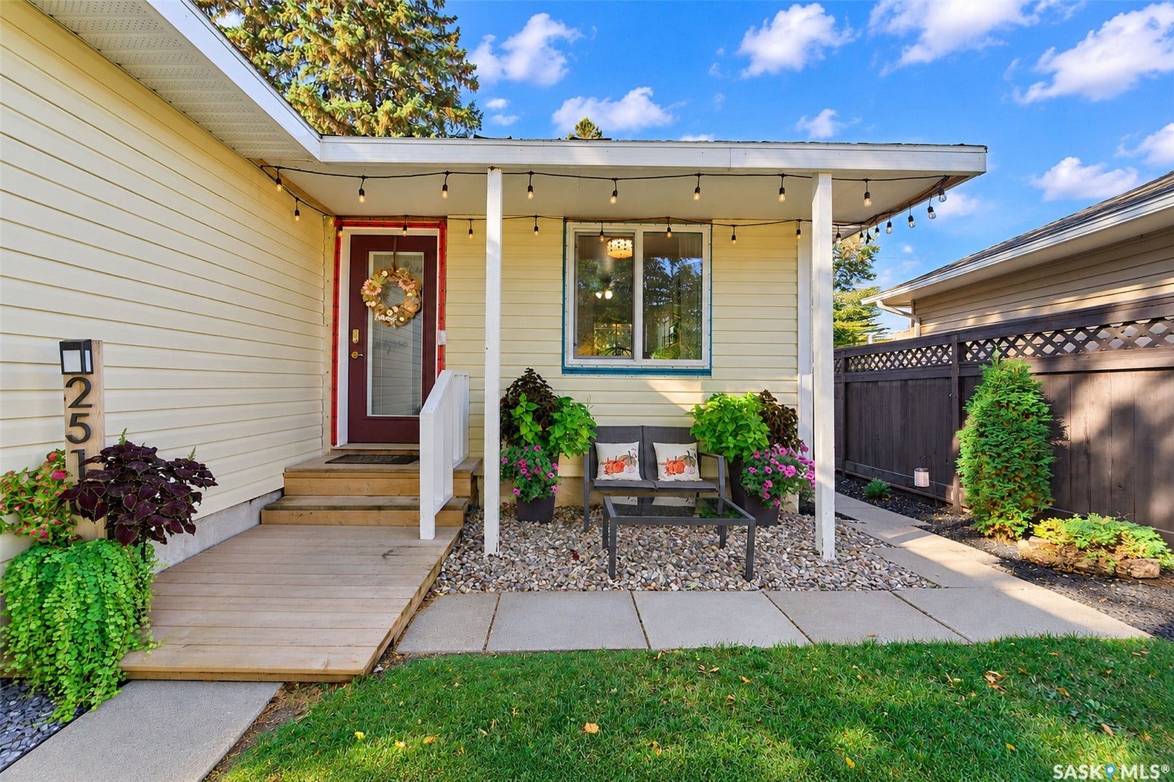 Front entry with a wood ramp and steps, covered porch, and gravel landscaping