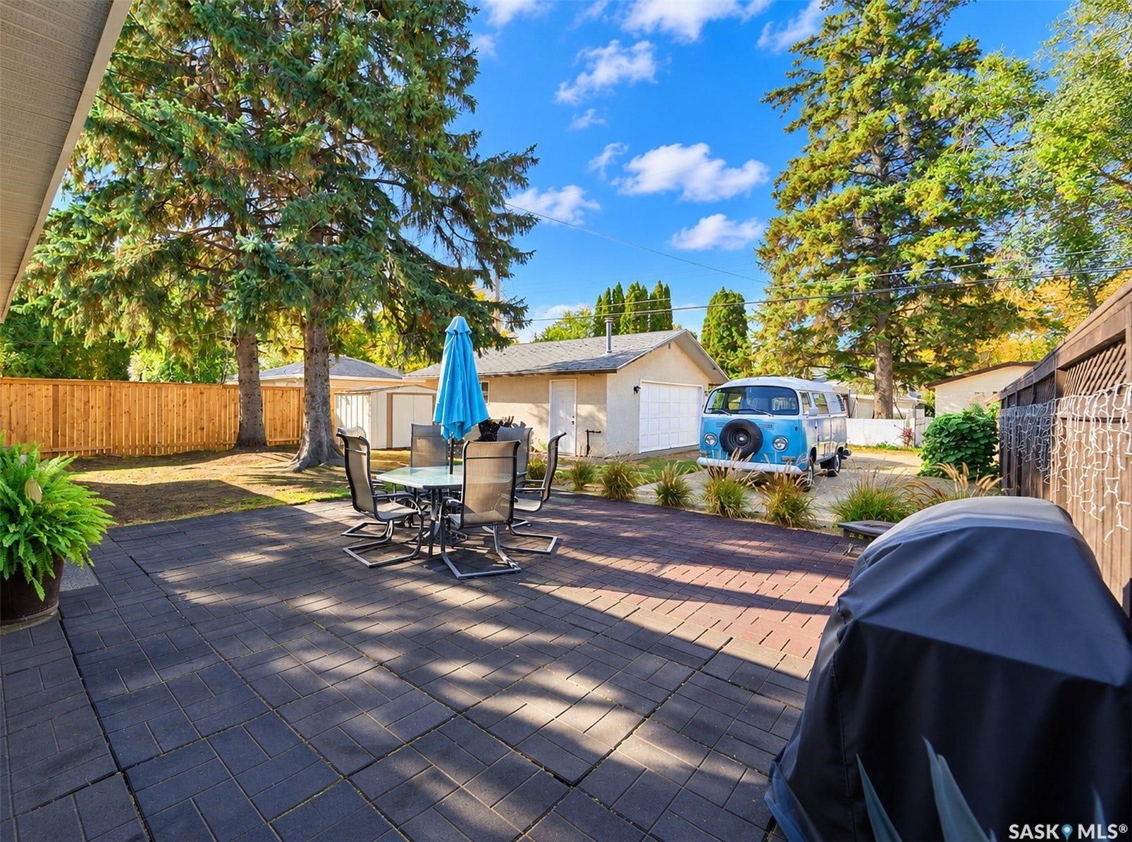 Expansive paver patio with mature trees and a private wood fence