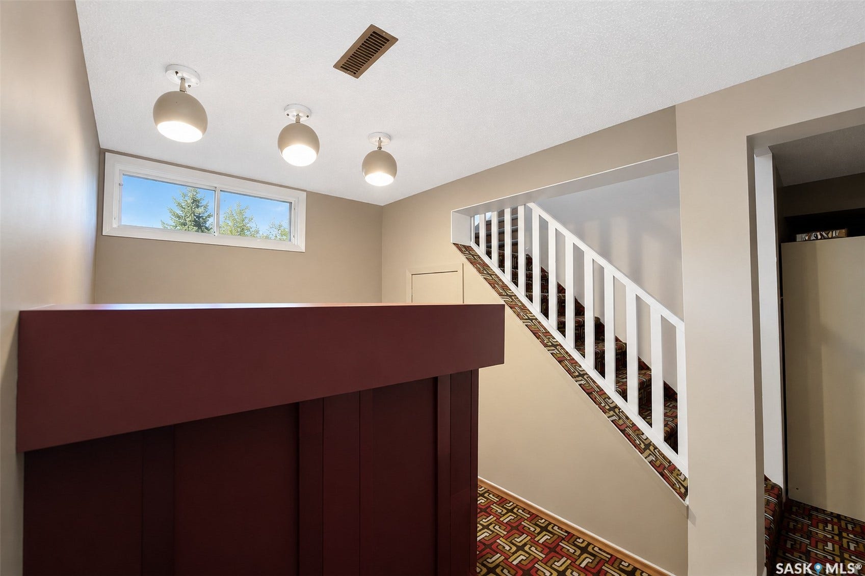 Staircase with white railing, built-in cabinetry, and overhead lighting