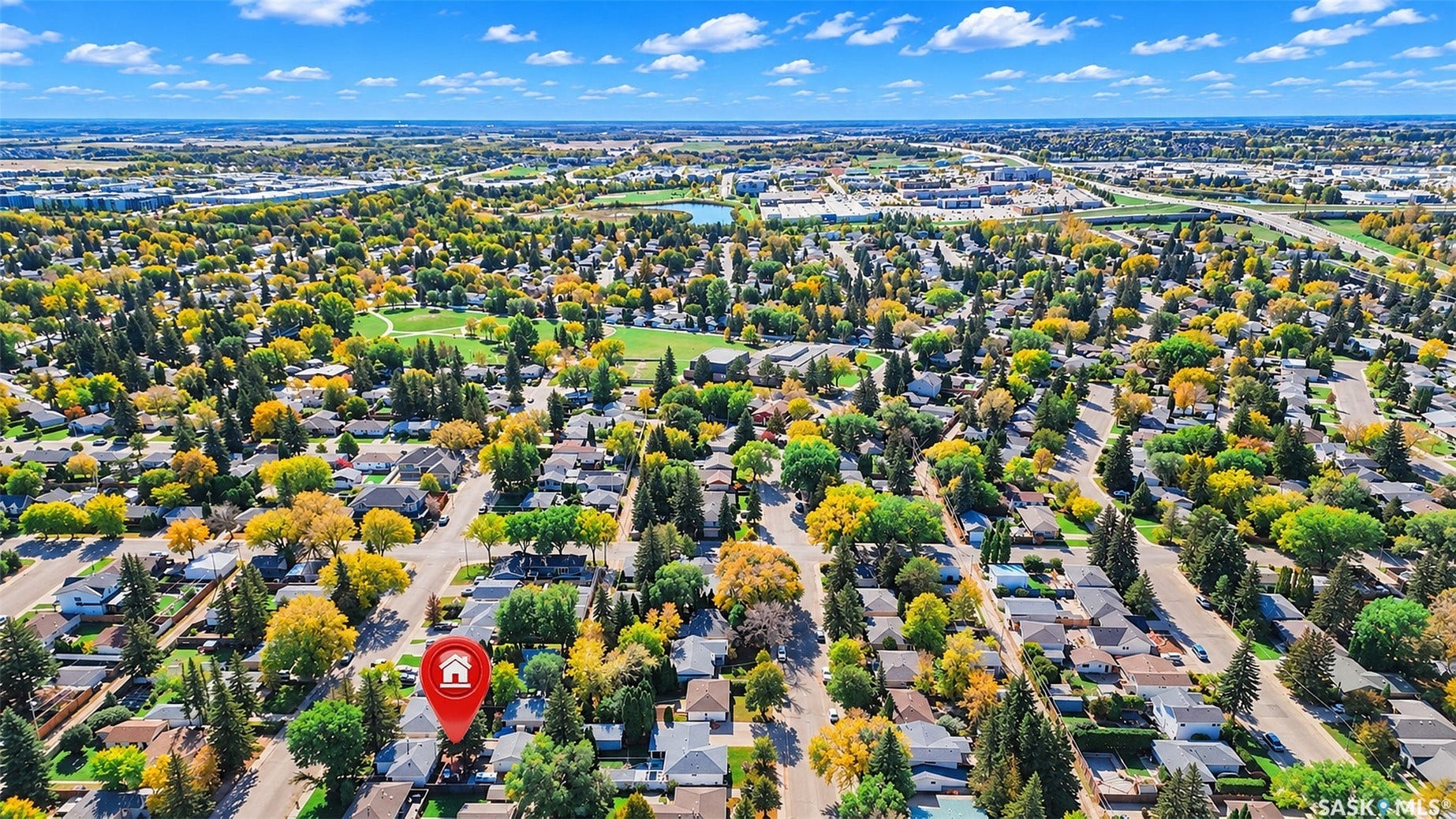Expansive residential neighborhood with mature trees, green spaces, and a visible body of water