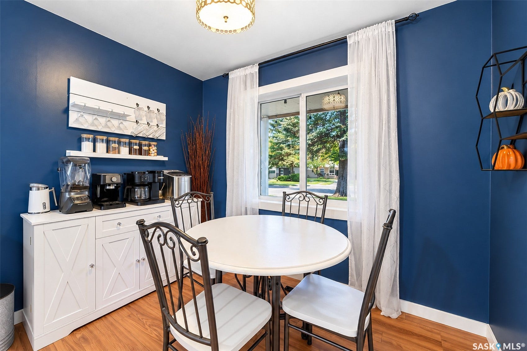 Wood-finish flooring, white window trim, and a built-in white console with X-panel doors