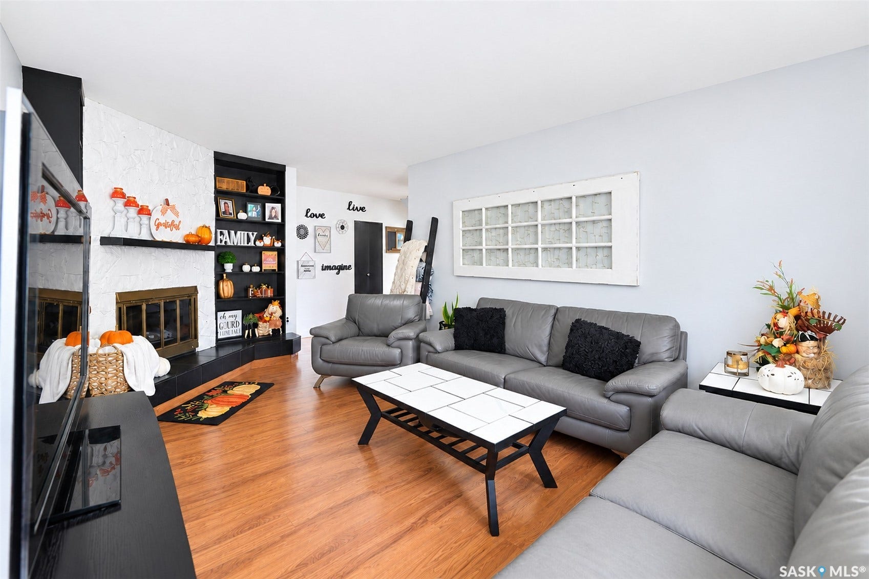 Wood-finish flooring throughout, with a white textured fireplace surround and a built-in shelving unit