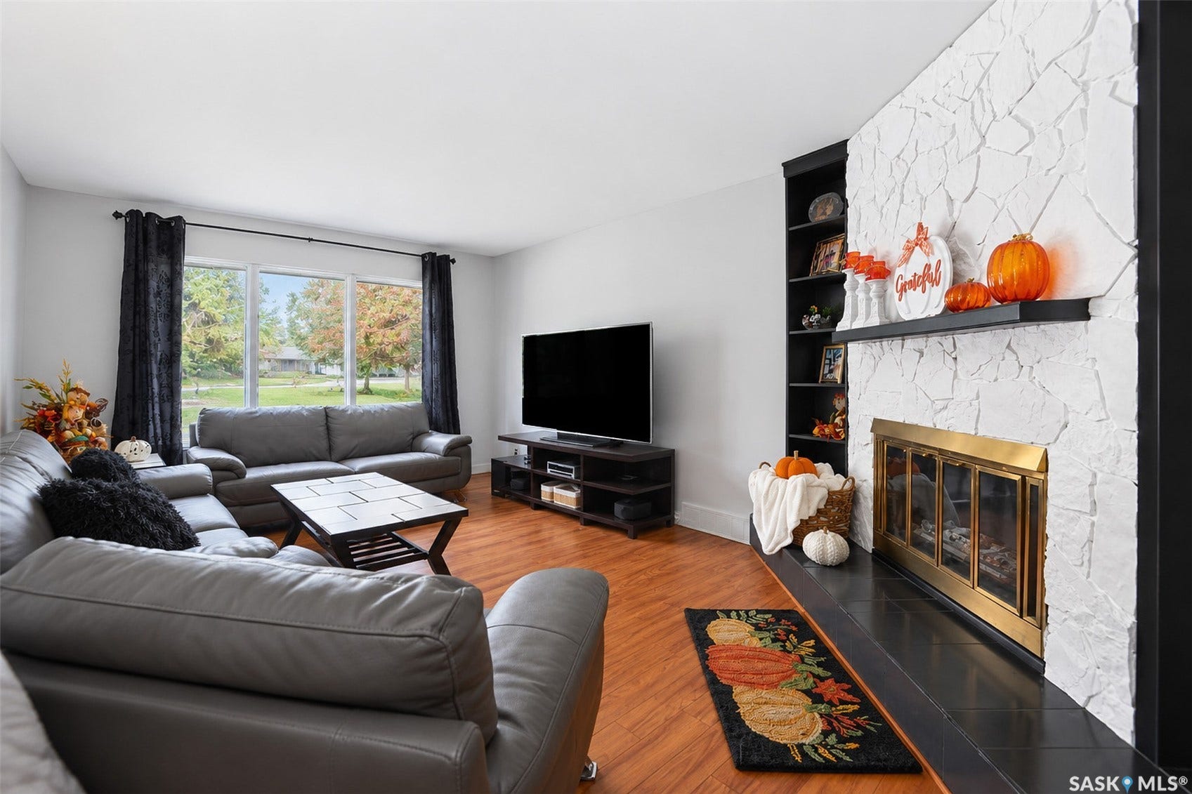 Living space featuring wood-finish flooring, a white textured fireplace surround with a black mantel, and built-in shelving