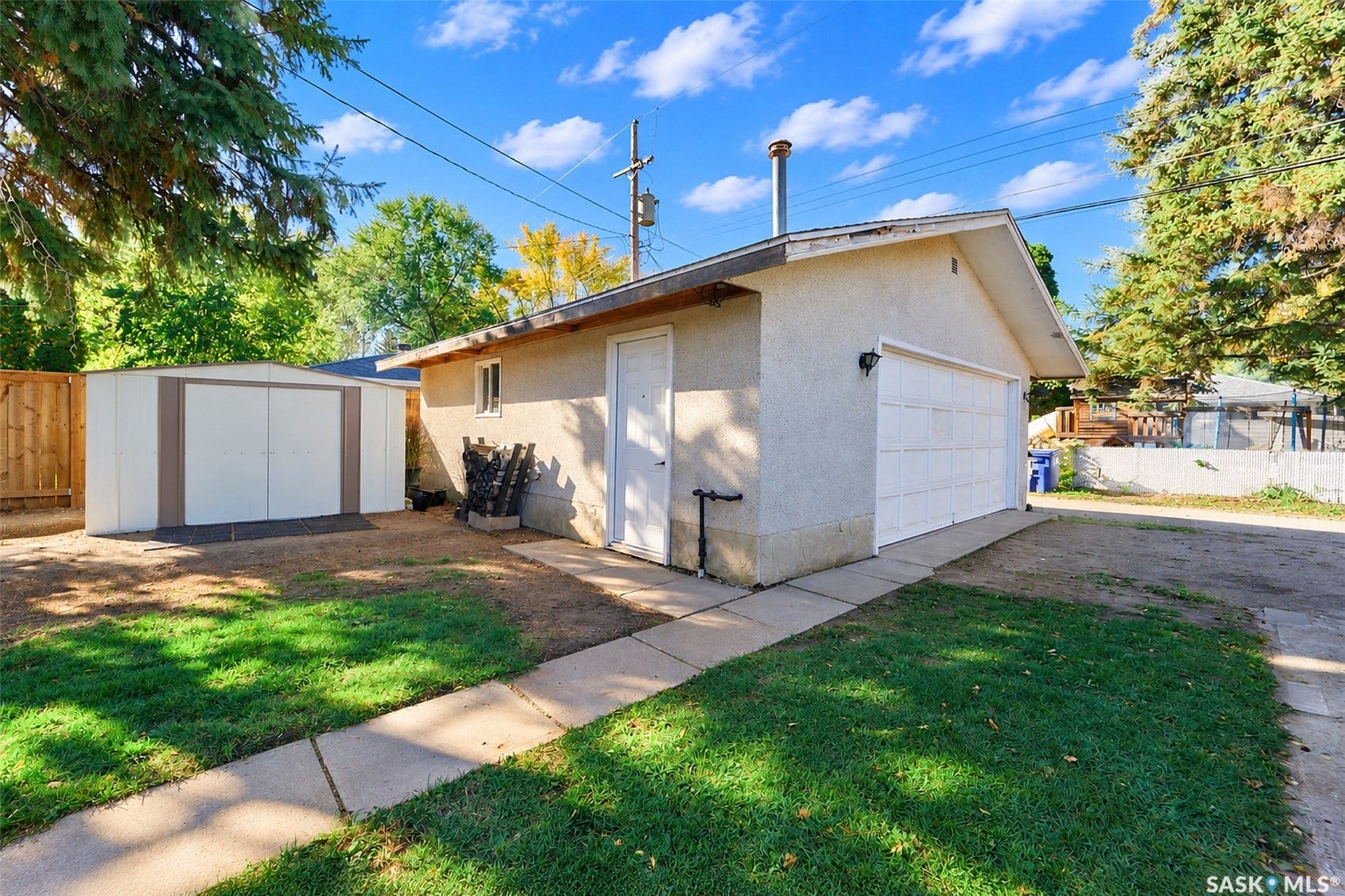 Detached garage with a roll-up door, stucco exterior, and a side entry door