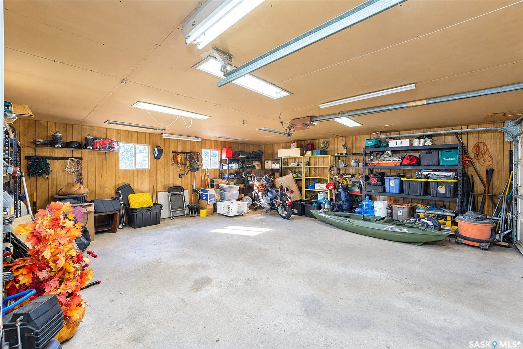 Spacious garage with wood-paneled walls, multiple windows, and a concrete floor