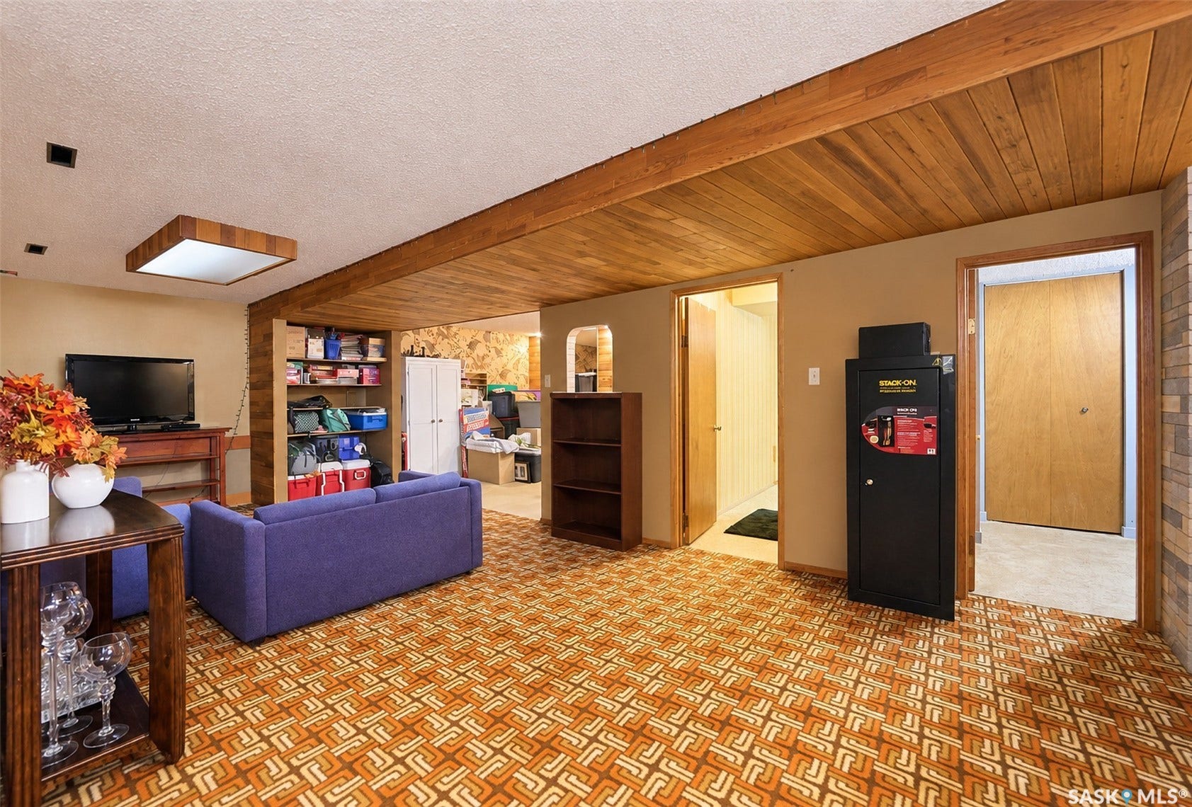 Wood-paneled ceiling with exposed beams, recessed lighting, and a flush-mount fixture
