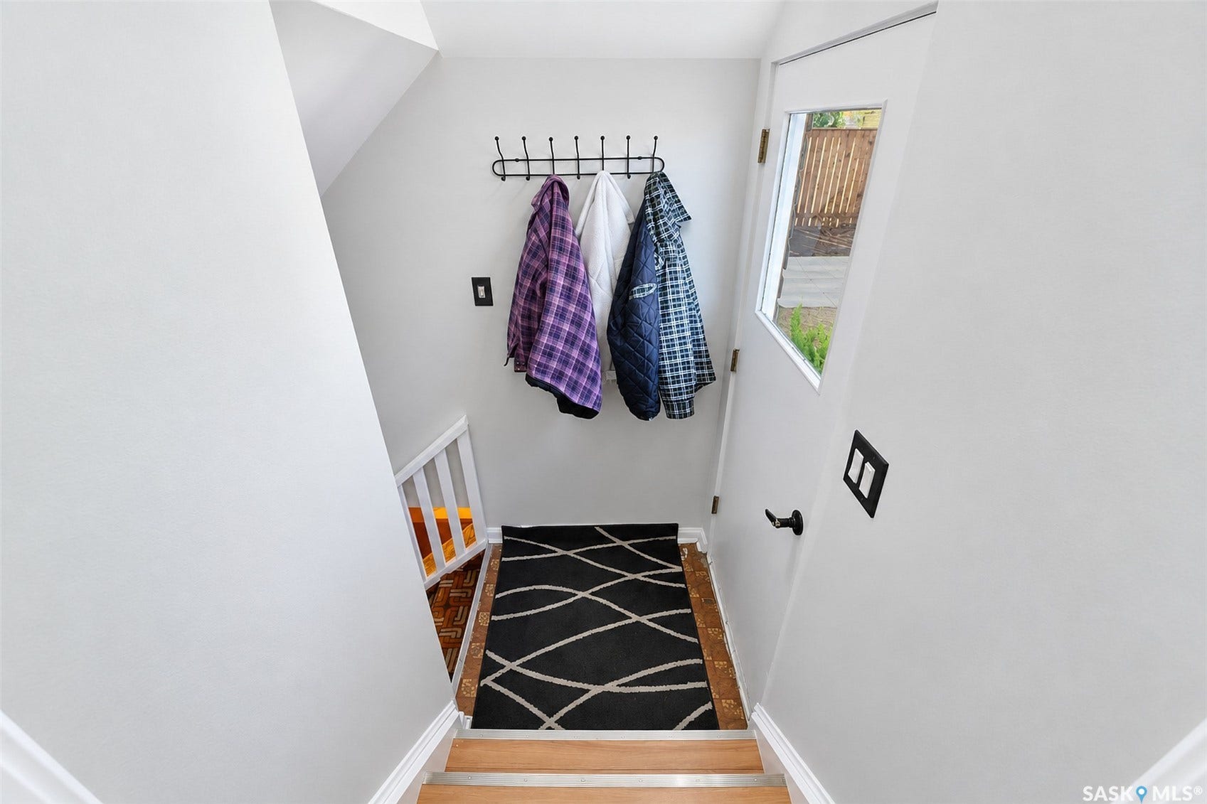 Wood-finish flooring at entry with light-toned stair treads