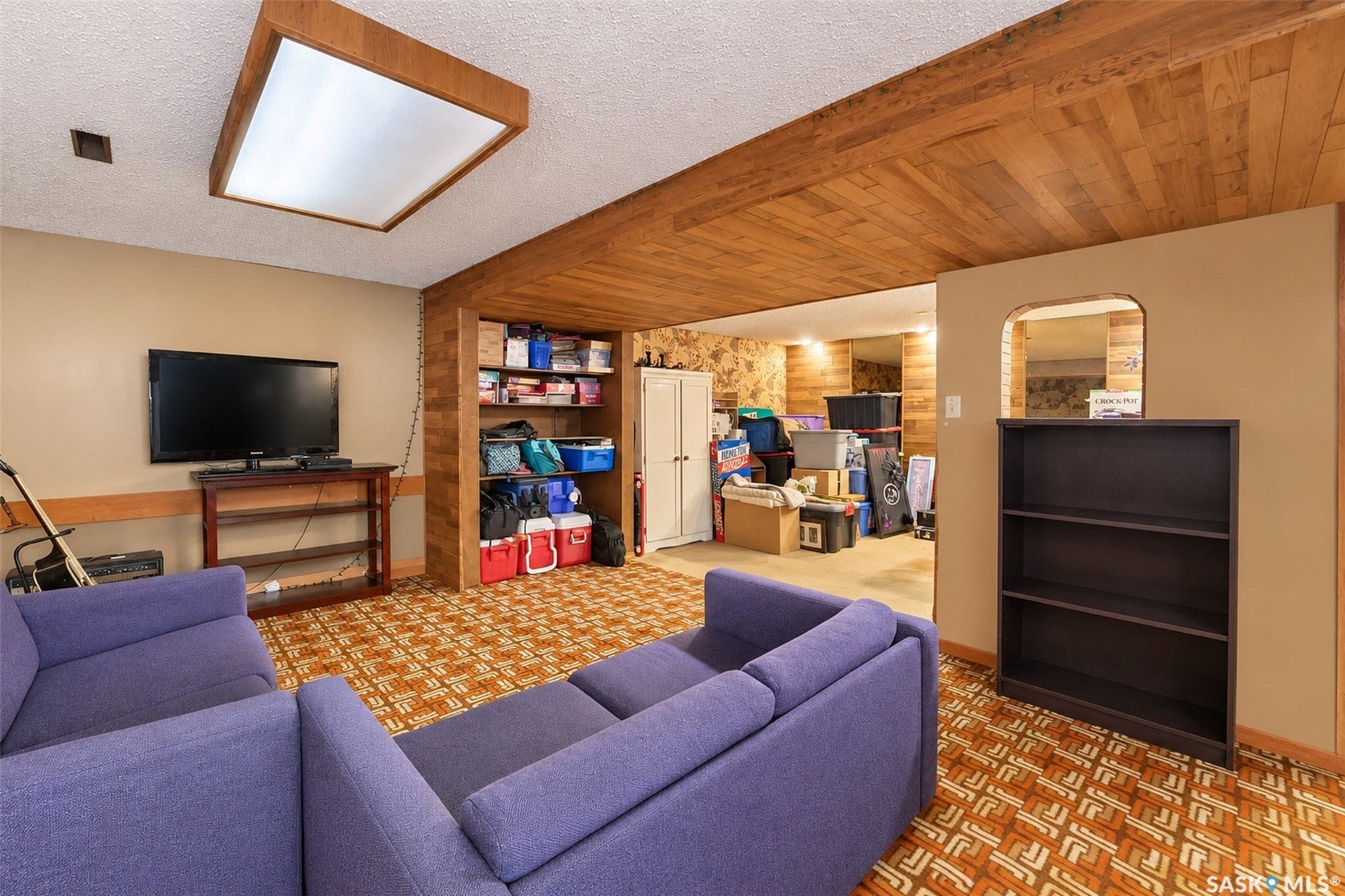 Recessed ceiling lighting, wood-paneled ceiling, built-in shelving, patterned carpet flooring, arched doorway